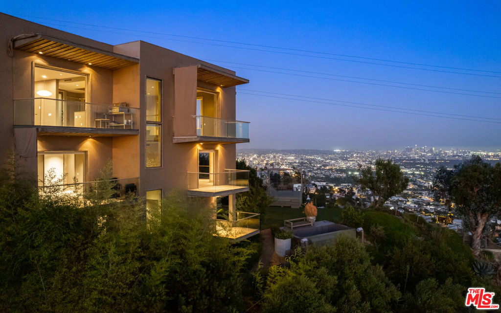 Situated high above the iconic Sunset Strip, this gated architectural masterpiece commands breathtaking jetliner views of the city skyline and the Pacific Ocean beyond. Meticulously designed to harmonize modern sophistication with the surrounding natural beauty, this three-bedroom with an office, five-bathroom residence spans over 3,400 square feet of refined living space. Flooded with natural light, the open-concept interior features disappearing pocket doors that blur the line between indoor and outdoor living, inviting in the shimmering city lights. Expansive limestone-clad balconies totaling approximately 900 square feet extend the living space into the open air, ideal for both relaxed lounging and sophisticated entertaining. At the heart of the home, the gourmet kitchen is a showcase of culinary artistry, appointed with top-tier appliances, custom cabinetry, and a generous central island that doubles as a gathering hub. The Primary Suite is a serene retreat, offering sweeping views from its private balcony, a spacious walk-in closet, and a spa-inspired bath with dual vanities and a soaking tub. Thoughtfully designed to embrace the outdoors, the property features a large hot tub, lush landscaping, multiple sitting areas, and a peaceful walking path leading to a scenic overlook. Additional highlights include a gated motor court with parking for up to six vehicles, a media area, and eco-conscious xeriscape landscaping. Located in the prestigious Viewmont Heights enclave, this rare offering is moments from world-class shopping, dining, and entertainment.