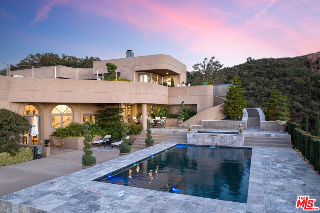 Property fell out of escrow, buyers were unable to perform. Designed in collaboration with renowned architects Roger M Yangita Associates and Cory Buckner, Architect, this property is nestled on approximately 37 acres of pristine landscape, this property transcends the ordinary, presenting itself as an exquisite residence. The long gated driveway, capable of accommodating over 30 cars, unveils a secluded haven. Boasting 360-degree views of the Santa MonicaMountains, this home offers a unique blend of natural beauty and architectural design. The interiors highlight a koi pond and curved walls of glass that create a harmonious connection with the surroundings. The gourmet kitchen is a chef's dream, equipped with top-of-the-line appliances, two prep stations, and a spacious island. This estate is perfect for enjoying the tranquility of the area and embracing a serene lifestyle. The house itself is a testament to durability and innovation, constructed using poured-in-place concrete and featuring a state-of-the-art fire suppression system for added safety. This residence encapsulates peaceful living, combining thoughtful design with a stunning backdrop to create an exclusive retreat. Per the sellers, the helipad is operational.