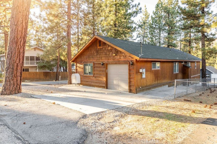 Pride of ownership shines throughout this beautifully maintained, single-story cabin built in 2007 and cherished by its original owner. Tucked among towering pines on a level corner lot near Maple Hill trails, this immaculate 3-bedroom, 2-bath home offers the perfect blend of mountain charm, comfort, and convenience. Step inside and be greeted by a light-filled open floor plan with tongue-and-groove knotty pine ceilings, warm wood finishes, and a cozy rock fireplace that anchors the spacious living area, ideal for relaxing after a day on the slopes or trails. The thoughtfully designed kitchen features solid wood cabinetry, granite-style counters, and modern appliances, seamlessly connecting to the dining area for effortless entertaining. Vaulted ceilings and large dual-pane windows bring in natural light and views of the surrounding trees, creating a sense of calm and connection to nature. The primary suite offers a peaceful retreat with its own private bath, while two additional bedrooms and a second full bathroom provide plenty of space for family and guests. The separate laundry room, attached one-car garage, and ample off-street parking—including space for a boat or small RV—add everyday practicality to this turnkey home. Outside, enjoy the mountain air from your covered front porch or stroll the quiet, paved neighborhood lined with mature pines. Whether you’re searching for a full-time residence, a weekend getaway, or a smart investment property, this home checks every box. Located just minutes from Big Bear Lake, ski resorts, hiking and biking trails, and the village shops and restaurants.