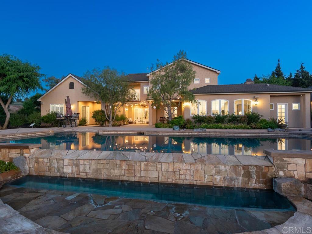 A French Country Dream with Views to Forever Tucked away in the peaceful hills of Bonsall, this French Country estate graces 2.5 acres of pristine Southern California countryside. With over 5,700 square feet of refined living, this 5-bedroom, 6-bathroom residence is more than a home—it’s a sanctuary. The Primary Bedroom is on the 1st floor. Architecturally designed for beauty, comfort, and inspired living. For those who are playful at heart, delight in a hidden “secret room,” a custom treehouse, an in-ground trampoline, and a private playground. A grand stone entry welcomes you into interiors that blend timeless elegance with contemporary convenience. With an elegant “Milk Glass” palette, upgraded lighting in the entry, dining, and bar rooms, the home exudes warmth and class at every turn. The heart of the home is a chef’s haven: an exceptional kitchen designed for both gourmet cooking and effortless entertaining. It boasts a commercial-grade Wolf range with French top, grill, and dual ovens, a sleek Sub-Zero counter-depth refrigerator, dual Miele dishwashers, a Miele steamer and sous vide, an instant hot water feature at the island sink, and a charming coffee bar for your morning rituals. Entertain with ease using the 330-bottle wine room and formal dining space—now enhanced with tile and a stacked stone fireplace for visual harmony. The primary suite offers a tranquil retreat with its own fireplace, spa-like soaking tub, walk-in closet, and a connected bonus room perfect for an office, studio, or gym. Motorized roller shades provide effortless light control. This luxurious home has an upgraded smart water system, including a Navien tankless water heater with recirculation pump to ensure comfort and efficiency throughout. The estate’s outdoor living is a masterclass in California lifestyle: a saltwater lap pool with beach entry and vanishing edge, poolside shower, a reflecting pond, and a fully equipped outdoor kitchen. A gated, smartphone-enabled entry and a certified ADT security system add peace of mind. A separate enclosed hacienda-style space with a doggie door creates an intimate and secure area for dining and recreation. Practicality meets abundance with a four-car oversized garage, attic storage with built-in access, 48 owned solar panels (with dual inverters and a solar-heated pool), water purification and conditioning systems, Nest-controlled HVAC zones, and Sense energy monitors for sustainable living. Outside, 170 mature Hass avocado trees yield thousands of pounds of organic fruit annually—an extraordinary feature for those who value both beauty and bounty.