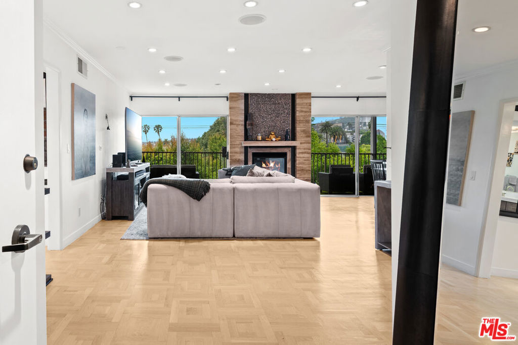 Elevate your lifestyle in this elegant top-floor condominium bathed in natural light and offering sweeping, panoramic views of West Hollywood, Beverly Hills, and the Hollywood Hills. This sophisticated residence boasts an expansive open-concept floor plan, where the spacious living room with a sleek fireplace and modern recessed lighting flows seamlessly to an oversized dining areaperfect for stylish entertaining. Floor-to-ceiling sliding glass doors open to a covered balcony, creating an effortless indoor-outdoor living experience. The well-appointed kitchen features new stainless steel appliances, generous cabinetry, and a charming walk-in pantry, offering both function and finesse. Retreat to the serene primary suite, complete with a luxurious en-suite bathroom featuring a beautifully upgraded double vanity and a custom walk-in closet with built-in organizers. A second renovated bathroom and a spacious guest room provide ample space and comfort with a walk-in closet. Additional highlights include central HVAC, in-unit laundry, and two dedicated parking spaces. Residents enjoy access to resort-style amenities, including a sparkling pool, sun deck, and stylish clubhouse. The unit also includes 2 tandem parking spots and a storage space in the garage. Ideally situated in the heart of West Hollywood, this chic condo is just steps from the city's most iconic dining, shopping, and nightlife. Moments from Cedars-Sinai, the Sunset Strip, and the Pacific Design Center, this is Westside living at its finest.