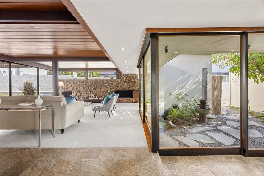 Designed in 1955, this architecturally significant residence reflects the influence of the Case Study movement and the early organic modernists who shaped Southern California architecture. The home’s warm redwood ceilings, exposed beams, expansive glass walls, courtyard garden, and long horizontal rooflines are hallmarks of the region’s most celebrated designers, including the work associated with Fred Briggs in North Tustin. This rare example of true mid-century design offers classic indoor-outdoor living framed by stone, wood, and beautifully landscaped garden courts.
From the moment you pass the private wall, the home reveals itself as a retreat of warmth and intention. Redwood ceilings and a centerpiece fireplace anchor the interior, while walls of glass frame sweeping courtyards bathed in natural light, turning each space into a living work of art. Timeless craftmanship and thoughtful updates elevate the experience.
Beyond the walls, the private vignettes connect living spaces to nature, inviting sunsets, starlit gatherings and the quiet rhythm of life. The sparkling pool offers serenity without pretense. 
Set on nearly 15,000 square foot lot, this home is a rare architectural treasure. Here you are part of a community that values privacy, design, and the spirit of California modernism. North Tustin is not just a neighborhood, but a place where identity is rooted in harmony with the land, timeless style, and the bounds of neighbors who appreciate both beauty and authenticity.
In a world of ordinary, this is extraordinary. A one-of-a-kind home that will speak not only to your sense of style, but also to your sense of belonging.
Incorporated in the lot size is ample space for another building, home addition, ADU, RV parking, garage, pickleball court...endless possibilities.