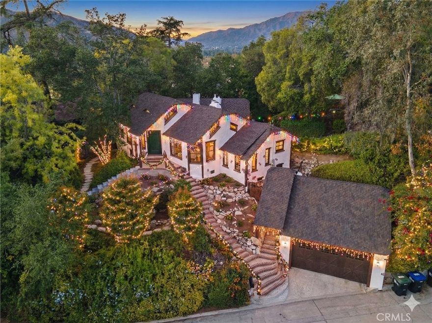 MILLS ACT APPROVED!! Home is now eligible for significant property tax reduction! The MacBride House (1924) — A rare 3-bedroom, 2-bathroom, 1,552-square-foot Storybook Tudor tucked into the trees of Glendale’s Verdugo Woodlands, revived through a meticulous two-year restoration that brought back its original soul while introducing modern comfort. Approved for the Mills Act, this home offers not only a connection to Glendale’s architectural heritage but also significant long-term property-tax savings. Built by an English craftsman who once worked for early Hollywood film studios, this home feels like it was lifted straight from Disney’s Snow White, with whimsical rooflines, arched doorways, and hand-carved details that radiate storybook magic. Inside, vaulted open-beam ceilings and leaded-glass windows fill the grand living hall with soft light that glows across refinished wood floors. The clinker-brick inglenook fireplace, flanked by original hand-carved benches, stands as the heart of the home and a masterpiece of 1920s design. The kitchen and baths have been restored with an artist’s restraint, new time period inspired wallpaper, reglazed sinks, new distressed vintage flooring in bathrooms and kitchen and new classic fixtures chosen in a way to preserve the home’s authenticity. Behind the beauty, every system has been thoughtfully modernized, including new copper plumbing, updated electrical, dual-zone HVAC, and an EV-ready two-car garage with a finished attic loft perfect for a creative studio or private retreat. The 10,226-square-foot lot unfolds into a private paradise of meandering garden paths, intimate patios, and mountain views that make you feel completely tucked away from the world while still only five minutes from the conveniences of modern life. Even the back staircase carries a homage of Glendale’s story, built from old railroad ties that reflect what once supported the trolley network that brought residents to this hillside haven a century ago. The Glendale Historical Commission has already met and formally recommended the home for Mills Act approval, with final City Council confirmation expected soon, offering the next owner both the pride of preservation and the potential for long-term property tax savings. The MacBride House is more than a home; it is a living story; a fairytale refuge that celebrates craftsmanship, imagination, and the timeless beauty that first made Glendale one of California’s most enchanting communities.