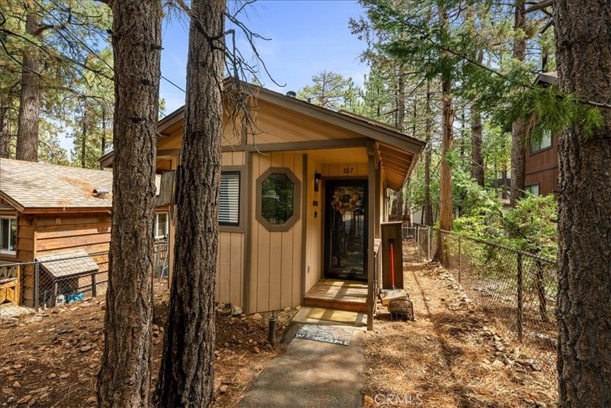 Nestled in the serenity of tall pine trees, this turnkey 2-bedroom, 1-bath cabin offers 774 sq ft of cozy comfort and rustic charm. Enjoy the warmth and ambiance of the beautiful rock fireplace with wood-burning insert, great for chilly mountain evenings. The light and bright open floor plan creates an inviting space, ideal for relaxing or entertaining. Step outside to the covered back deck—an ideal spot for outdoor gatherings or peaceful mornings with coffee. Sold fully furnished, this home is truly move-in ready! Features include a new hot water heater, efficient wall heater, plantation shutters, and a handy shed for extra storage. Whether you're looking for a weekend escape or a full-time retreat, this cabin has it all!