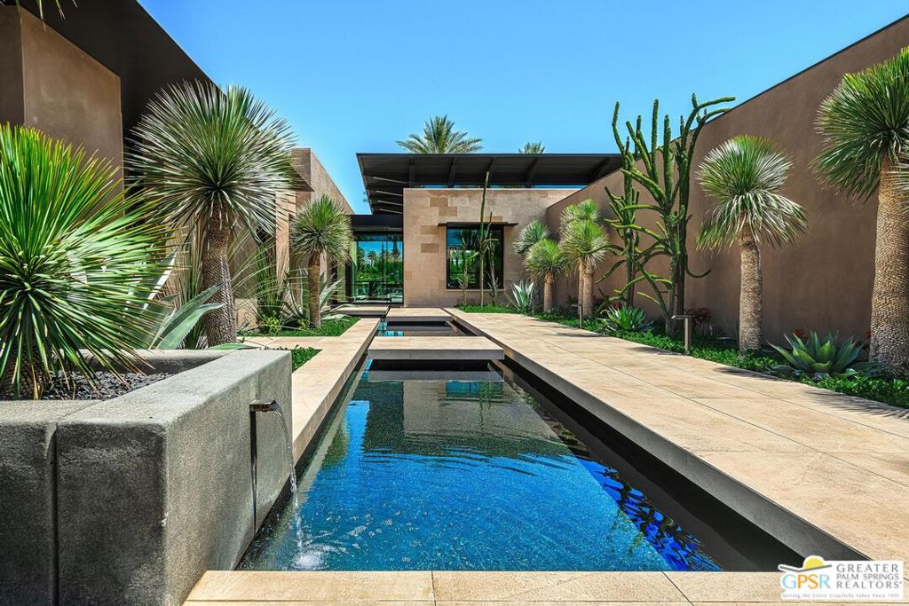 Quite simply one of the best offerings ever at world class Toscana County Club in beautiful Indian Wells, CA. This published architectural home features the finest materials and superb craftmanship creating an idyllic setting blending the indoor and outdoor. A series of "lily pad" concrete walks lead you to the main entrance of this inviting home. Transom windows allow more light to flood from all directions of the property which was meticulously studied as part of the design of the property. Walls of glass disappear through much of the home blending the warm inviting interiors to the exterior spaces. Mixed use of woods, stone and glass with custom steel work throughout the property and structural as well. Multiple lounging areas and two conversation firepit areas as well as outdoor dining pavilion with built in heaters and misting system are enhanced by the infinity edge pool and zero scape spa. The main living spaces are open with a lounge area opening to the reflecting pools and sounds of perfectly pitched waterfalls. Two offices plus a cozy den for viewing your programs and additional bedroom suite in the main house. A two bedroom, two bath with living room attached guest house offers privacy for all. The primary suite and spa bath features double separate closets and water closets as well with heated flooring and a soaking tub. Simply the best millwork and finishes we have seen in this incredible offering with owned solar system, oversized four car garage with car chargers and vacuum system plus two cart golf cart garage totally roughly 1600 square feet (in addition to the 5762 square feet of living space and almost half acre lot). This custom home is located in one of the top clubs in the Coachella Valley featuring exceptional amenities including, 2 Jack Nicklaus Signature Golf Courses, 5-Star Spa, State-of-the-Art Fitness Center, Pool, Bocce, Tennis, Pickle Ball and multiple dining venues and two dog parks - something for everyone! Simply the best of the best.
