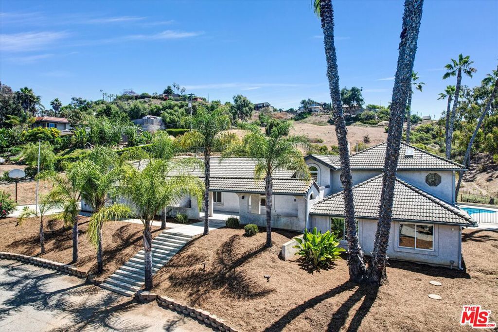 Looking for the peace of country living without sacrificing city convenience? Welcome to your private hillside retreat at 614 Valley Dr where space, comfort, and opportunity converge. This beautifully maintained 4-bedroom, 3-bath home sits on a fully fenced 1.4-acre lot, offering rare privacy, serene natural surroundings, and expansive views of the open space beyond. Inside, the open-concept layout is flooded with natural light and features spacious living areas, upgraded designer lighting, and a flowing floor plan perfect for everyday living and entertaining. The heart of the home is an all-white, bright updated kitchen, complete with a brand-new refrigerator ideal for home chefs and casual gatherings alike. Upstairs, the primary suite is a true sanctuary with a recently remodeled en-suite bath and a private balcony overlooking the pool and surrounding hillsides. Downstairs, you'll find three generously sized bedrooms, an updated bathroom, and a versatile second living space ideal for guests, kids, or multi-generational living. Outdoors, enjoy resort-style amenities with an in-ground pool, covered patio, and vast open yard perfect for horses, RV or boat storage, or even building an ADU. The owned solar system, large attached 3-car garage, and separate storage shed add functionality and long-term value. Whether you're an end-user seeking space and flexibility or an investor looking for income potential and ADU opportunities, this property delivers. All just minutes from Downtown Vista, top-rated schools, Brengle Terrace Park, shopping, and a short drive to the beach.