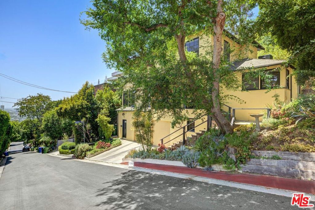 c.1947 Traditional with cinematic charm. Elevated above the Sunset Strip with dazzling city views and tucked into the hills of one of LA's most iconic enclaves, this home is where vintage soul meets timeless Hollywood magic. 2-bed, 2-bath plus private guest quarter and an office perfect for creative living. A formal entry leads into a sunken living room, where tall original windows bathe the space in golden light, and a central brick fireplace anchors it with warmth and history. The kitchen is a preserved vintage treasure: powder blue tile, corner windows, and an original O'Keefe & Merritt oven. Hardwood floors flow throughout, guiding you to a curved staircase and an airy primary bedroom wrapped in glass and commanding panoramic views. Outside, a garden patio feels like a tucked-away cafe in the Italian countryside, climbing bougainvillea, hanging string lights, and dappled sun set the stage for lingering dinners and coffee, you'll never know you're only a few steps away from the legendary Sunset Strip. Below, a separate guest quarters with its own bath offers privacy, while a nearby bonus room is ideal for a home office, gym, or creative studio. In the center of everywhere you want to be, this home is your next chapter. Public records show 1564 sq ft. Vendor measurements are 1830 sq ft including the guest quarters and office. Buyer to verify accuracy.