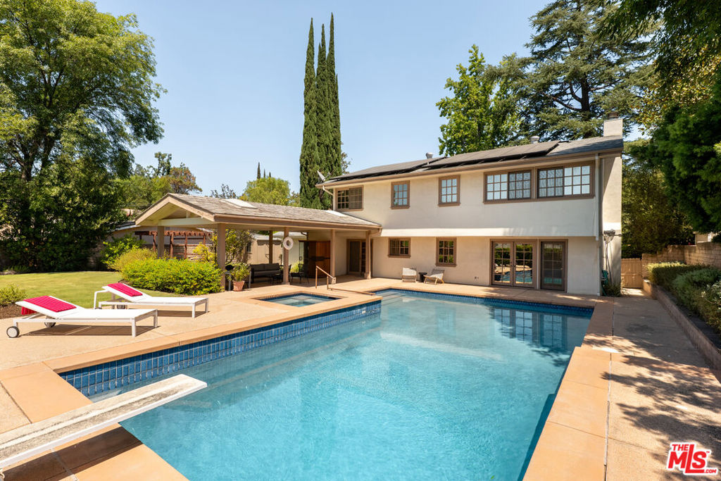 Charming 5-bedroom pool home with paid solar in a quiet Woodland Hills neighborhood! Located just west of Valley Circle Rd in the El Camino school district, this home exudes charm and warmth, with a thoughtful layout. The entire lower level, which opens to the resort-like back yard, has exceptional flow for casual, or formal, entertaining. Once outside the options are truly endless: lounge on the upper level of the pool deck, fire up the grill (with direct gas line) and dine under the covered patio, hop in the hot tub, run free in the rear grass, meditate in the rock garden, or take an infrared sauna (included). Upstairs are all 5 bedrooms, featuring a primary suite with gorgeously renovated bath and great views of the hills & another bedroom with built-ins that is used as an office/den. Back downstairs is a large living room with reading alcove, fireplace and window seat, a modern kitchen with a large island, dining room and eat-in area and a recently remodeled full bath. A large 2-car garage has two walls of storage and a recently added washer/dryer. This home checks all the boxes in one of Woodland Hills' most desirable neighborhoods.