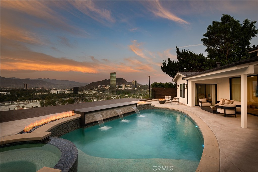Tucked away in the coveted hills of Studio City, this refined and private residence showcases sweeping panoramic views and an impressive array of upscale upgrades and designer finishes. From the moment you arrive, the home’s thoughtful layout and sophisticated aesthetic make a lasting impression. An open-concept floorplan seamlessly connects the expansive kitchen - appointed with a large center island, custom cabinetry, premium Viking appliances, and an elegant dining area - to a warm and inviting family room. Walls of glass flood the space with natural light and frame breathtaking city and mountain vistas, opening to a tranquil outdoor sanctuary. Designed for both effortless entertaining and everyday relaxation, the backyard features a PebbleTec pool and spa, expansive deck, built-in BBQ, and multiple lounge areas, including a rooftop deck ideal for sunset views. The luxurious primary suite boasts two generous walk-in closets and a private balcony with unobstructed views. Additional amenities include a gated driveway with parking for 10+ vehicles, integrated Sonos sound system, striking marble-surround fireplace, pool safety net, water softener/salt system, steam shower, soaking tubs, custom dining room bar, home automation, and newly upgraded systems including electrical, plumbing, and HVAC. Ideally situated just moments from Ventura Boulevard’s premier shops, dining, cafes, and farmers market, and with convenient access to the 101 freeway. This exceptional residence offers the perfect blend of privacy, luxury, and location. More than a home, it is a serene retreat in one of Studio City's most sought-after neighborhoods.