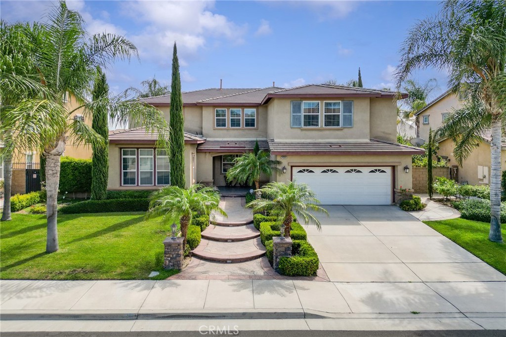 Welcome to this stunning two-story home that effortlessly blends timeless curb appeal with modern comfort and versatile living. The beautifully landscaped front yard, highlighted by stately palm trees and a stone-accented walkway, creates a warm first impression. Inside, soaring ceilings and natural light complement an open-concept layout perfect for both daily living and entertaining. The formal living and dining rooms flow seamlessly into a gourmet kitchen featuring granite countertops, stainless steel appliances, and a center island. A casual dining area opens to the backyard, while the inviting family room offers a cozy fireplace and large windows. A convenient main-level bedroom and ¾ bath are ideal for guests or multi-generational living. Upstairs, you will find four bedrooms, including a spacious primary suite with a luxurious en-suite featuring a hot tub, walk-in shower, dual vanities, and a walk-in closet. An additional bedroom includes its own private bath, while a generous loft provides flexible space for a media room or home office. Dual staircases add both privacy and convenience when accessing the second floor. Step outside to a private backyard retreat with lush tropical landscaping, fruit trees, an expansive stamped-concrete patio, and plenty of space for entertaining or unwinding. Completing the home is a 3-car tandem garage and an ideal location directly across the street from the park. With its thoughtful design, versatile spaces, and stunning backyard, this move-in-ready home is the perfect balance of elegance, comfort, and functionality—waiting for its next owners to call it home.