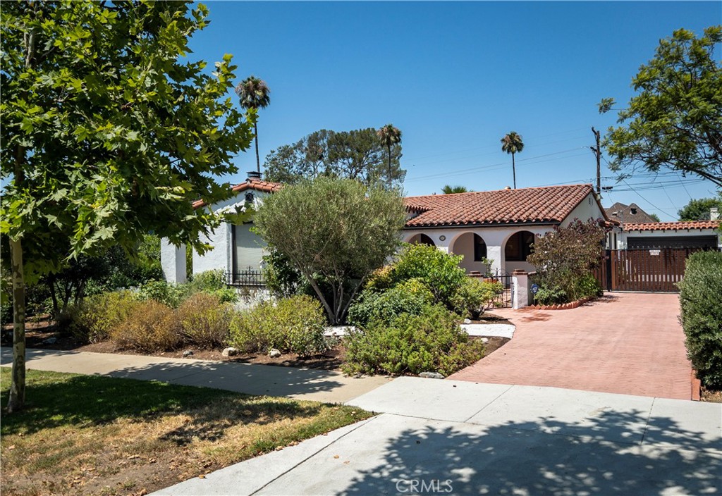 Nestled on a picturesque, tree-lined street in one of Northwest Glendale’s most sought-after neighborhoods, this beautifully updated Spanish-style home offers a perfect balance of timeless charm and modern convenience. Boasting over 2,400 sf of living space on a generous 9,199 sf oversized lot, this 3-bedroom, 3-bathroom residence is both spacious and tastefully designed. The expansive living room welcomes you with a stunning fireplace, custom built-ins, and rich mahogany wood floors that add warmth and elegance. The chef’s kitchen is equipped with stainless steel appliances, ample cabinetry, and a thoughtfully designed layout ideal for both daily living and entertaining. A light-filled den/family room opens directly to the backyard, providing flexible space for relaxation or gatherings. Each of the three bathrooms has been tastefully renovated with premium finishes. The primary bathroom offers heated floors, a soaking tub and separate shower, evoking a spa-like ambiance. The spacious bedrooms are complemented by well-appointed closets for ample storage. Recent retrofitting upgrades and fully paid-off solar panels contribute to long-term energy savings and peace of mind. Step outside to your own private backyard oasis—an entertainer’s dream featuring a sparkling pool, a fully equipped outdoor kitchen, and a variety of mature fruit trees. The oversized driveway offers additional parking, complemented by a detached 2-car garage with a finished workshop, perfect for a studio or home office. Conveniently located just minutes from Kenneth Village, local shops, dining, and major studios, this home delivers a rare blend of comfort, character, and classic California living.