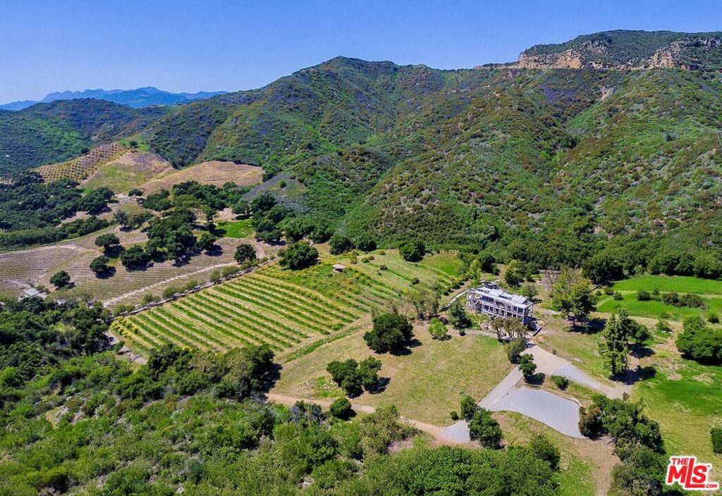 Discover an extraordinary contemporary retreat and private compound in the Malibu Mountains - Malibu Orchard Estate. This stunning 32-acre sanctuary seamlessly combines privacy, bunker-level safety, and sustainability, offering the perfect blend of seclusion and accessibility. Built to the highest fire and seismic safety standards, the Main Residence features a fortified concrete moment frame, ensuring both durability and fire protection. Set at the end of a private gated road, this exclusive property boasts expansive views of pristine wilderness, running creeks and orchards. With 8,182 sq. ft. of interior space and 3,100 sq. ft. of exterior terraces, this three-story contemporary home presents a rare opportunity to customize a premier Malibu estate. Currently 83% complete, the Main Residence includes 2 bedrooms and 3 bathrooms, with the flexibility to convert the permitted family room and powder room into a third bedroom and bathroom. Additionally, two powder rooms are permitted on the first floor. Along with an existing pool, pool terrace and pool house to be renovated. A planned 2-bedroom, 2-bathroom guest house (not yet permitted or built) has the potential for a third bedroom. Further accommodations include a one-bedroom, one-bathroom cottage and a pool house with an extra bathroom. Designed for an exceptional lifestyle, the estate features a resort-style pool, a pool house, and a thriving persimmon orchard ideal for farm-to-table living. A proposed solar farm and horse barn with a corral promote off-grid sustainability while offering the enjoyment of horseback riding. A seasonal natural stream enhances the estate's peaceful ambiance. Inside, the residence is crafted for refined living and entertaining, with a stylized foyer, a cascading water feature, and an all-glass elevator. The open-concept living and dining areas, featuring a second cascading water feature, maximize breathtaking views, while the chef's kitchen, family room, and game room seamlessly transition to outdoor patios. The lower level includes a three-car garage with EV charging, a mudroom, and ample recreational storage. For sale at $8 million with over $13.5 million already invested and an estimated 75% of building costs paid, this is a rare opportunity to create a private sanctuary, vineyard retreat, or entertainer's paradise. Just minutes from world-renowned beaches, dining, and shopping, and only 10 minutes from the Pacific Coast Highway and 16 minutes from the 101 Freeway this property lies at the crossroads of tranquility and convenience.