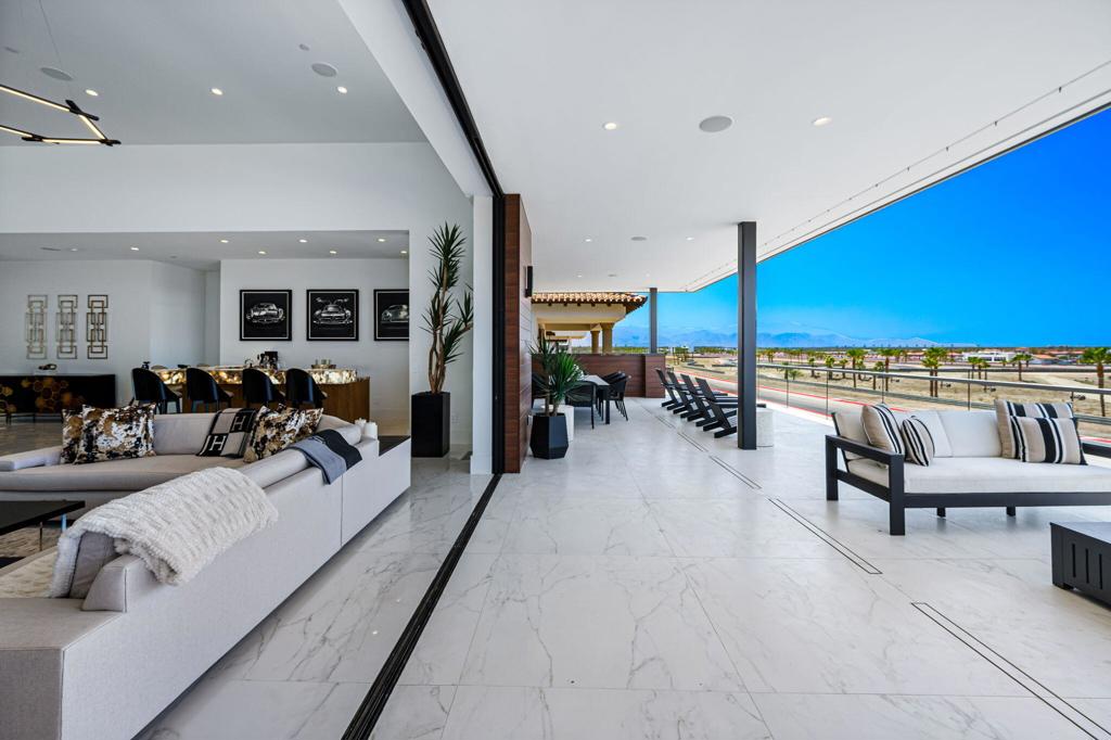 Live life in the fast lane at The Thermal Club, a premier motorsports community where luxury and performance meet. Situated in a coveted on-track location, this 4-bedroom, 5.5-bath estate offers approx. 9,203 SF of combined living and garage space. Enjoy panoramic views of the circuit and surrounding mountains from retractable glass doors that open to a misted patio with built-in BBQ. Inside, features include porcelain tile floors, a built-in bar with Sub-Zero fridge and ice maker, Crestron smart system, surround sound, power shades, and heated bathroom floors. The chef's kitchen features Wolf appliances and a Sub-Zero refrigerator, while the primary bath includes a walk-in shower and soaking tub. Ownership includes access to club amenities: five miles of private track, multiple circuits, two clubhouses, dining venues, spa, fitness center, karting, tennis, 48-villa hotel, and more. A $200,000 initiation, $2,400/month dues, and $350/month ground fee apply. Buyer to verify all details