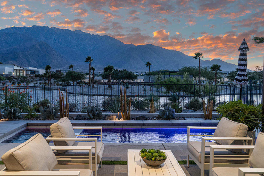 What is it that makes living in Palm Springs so special? It is the life style, basking in sun pool side, with the desert's natural beauty as backdrop . Welcome to an exceptional three-bed, three-and-a-half-bath residence spanning 2,800 square feet at Miralon, where contemporary styling sets the tone. From the start, style guides the Miralon experience, and entering at one of secured gates, you have the rolling hills of an olive grove and a stunning clubhouse with pool and lounge areas.Thoroughly upgraded finishes and upgrades set this property apart. At its heart, this home features a dramatic two-story main living area with a tiled wall and columns of windows framing breathtaking mountain views and welcoming natural light. Enjoy a modern kitchen with an extended island accommodating four seats, complemented by high-end Bosch stainless steel appliances. The dining area seamlessly connects to an outdoor dining set and barbecue space, amenities enabling a lifestyle in which time is spent outside.Adjacent to the great room, on the main floor, is the primary suite facing due west, looking out on a charming view of the lake outside, and the dramatic mountains due west beyond. With its unique wallpaper, one among many stand apart finishes, the primary has a luxurious bathroom featuring double vanities and a spacious uniquely tiled walk-in shower with bench, and an oversized walk in closet. Outside, the in-ground pebble tech pool and spa with enhanced lighting overlook the lake with private park, and jaw dropping mountain panoramas. Multiple seating areas, including one around a fire pit make this an exceptional outdoor experience.On the loft level upstairs, these views are even more dramatic from the family room and the flexible third bedroom currently serving as a fitness space, and a separate full bath. Additional highlights include a finished garage with epoxy flooring and twenty paid solar panels. A truly special home awaits at Miralon.