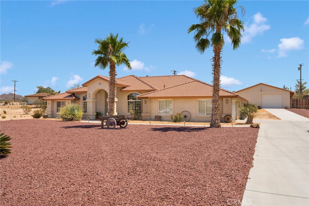 Custom built home offered for the first time on the market. This Deserada home has all the signature features that you'll love: arched windows, open flowing floor plan, pot shelves, spacious bedrooms, three living areas and large kitchen. This property is over one acre. A 1280 square foot RV garage with workshop is a hobbyist’s dream with parking for at least 4 inside the building, in addition to the three car attached garage. Tons of exterior improvements, concrete driveways, and dual drive in access at the front and side of the lot. The house has been meticulously maintained by the original owner. The flooring has been upgraded to wood-look plank tile flooring. Ceiling fans throughout, built-ins and lots of storage. The primary suite features a sliding glass door to the rear patio. The en-suite has a large walk-in dressing room closet, seated vanity with drawers, soaking tub with spa deck, dual sinks, private water closet, and spacious low berm shower stall. Indoor laundry with cabinets in its own room. 220v in workshop and house garage. Custom garage floor surface installed in house garage. Storage room in the house garage. Parts storage shed in upper yard for even more storage for projects and hobbies. This Desert Knolls location affords magnificent mountain views, and close proximity to shopping, big box retail, theater, dining, grocery, and many other conveniences. Lovely desert landscape. Fully fenced with stucco wall across front and along driveway for fabulous curb appeal. This home is certainly a stand out amongst the rest. Don’t miss your chance to have a beautiful home with that hard to find workshop RV garage building.