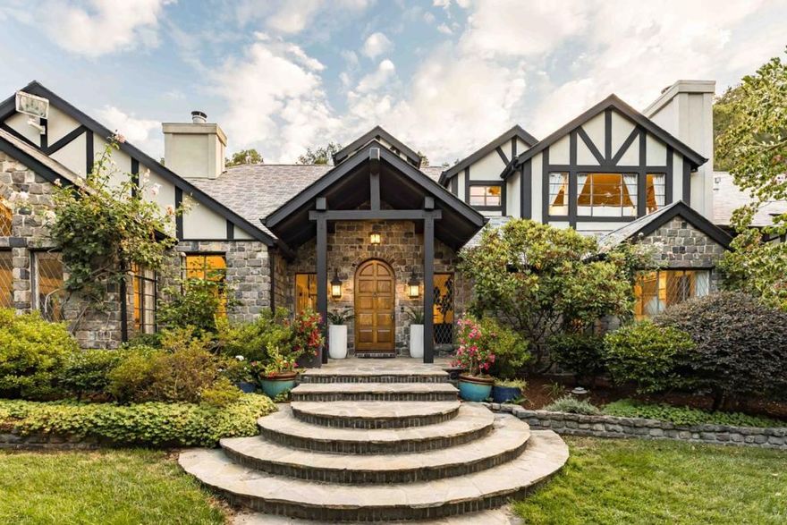 Shaded by towering redwoods and nestled beside the Palo Alto Hills Golf & Country Club, this exceptional Tudor estate offers a rare blend of grandeur, privacy, and natural beauty. Set on a full acre, the main home spans over 6,200 square feet of light-filled interiors with soaring ceilings, fine millwork, rich hardwood and tile floors, and expansive formal spaces ideal for entertaining. A walk-out family room and chef's kitchen with premium appliances provide comfort and functionality, while multiple fireplaces add warmth and charm. The flexible layout includes a bedroom that doubles as an office, and a luxurious primary suite. Multi-level, masterfully landscaped grounds feature a saltwater pool by a peaceful waterfall, an outdoor kitchen, fire pit patio, pool house with sauna and fireplace, and a separate 1-bedroom guest house. With AC, a 3-car garage, and a prized Palo Alto Hills location, this home offers the ultimate in private, elevated living.