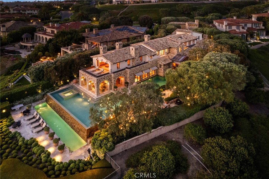 Positioned within the ultra-exclusive, guard-gated enclave of Pelican Crest, this unparalleled legacy estate is a rare offering of architectural significance, timeless design, and world-class craftsmanship. Conceived by internationally renowned architect Richard Landry, with interiors curated by celebrated designer Craig Wright, and brought to life by esteemed builder John Fenton, this residence sets a new standard for coastal luxury. Encompassing approximately 13,206 square feet on an ultra-premier ~half-acre lot, this landmark estate captures unobstructed panoramic views stretching across the Pacific Ocean, Catalina Island, Newport Harbor, Pelican Hill Golf Course, and the exceptional city lights along the California coastline. Among the finest parcels ever to come to market, this estate offers an unmatched sense of place and exclusivity. Evoking the ambiance of a secluded Tuscan villa, the grounds are richly adorned by lush landscaping, tranquil pathways, and mature olive and melaleuca trees, all enhanced by atmospheric lighting and expansive entertainment terraces. A serene entry koi pond, detached guest house, and a 16th-century Venetian fountain enrich the sense of quiet opulence. Inside, the home reveals six bedrooms, six full baths, and three powder rooms, with soaring ceilings, grand-scale living areas, and seamless indoor-outdoor flow. The private lower level offers an immersive experience like no other: a vintage-inspired theater with hand-painted ceiling murals, crystal lighting, a speakeasy bar with glass walls peering into the pool, a temperature-controlled wine cellar, full gym, massage room, steam shower, and lounge areas that echo the mood of an elite members-only club. Anchoring the estate is a multi-level, infinity-edge pool clad in bespoke Italian glass mosaics, a true centerpiece. A covered loggia offers an open-air living room with breathtaking coastal views, ideal for year-round enjoyment. Created for grand-scale entertaining and intimate everyday living alike, this estate is the crown jewel of Newport Coast destined for the most discerning buyer. With immediate access to Pelican Hill Golf Course & Resort, world-class shopping, award-winning schools, and the finest of coastal Southern California living, this is more than a residence, it’s a once in a lifetime legacy offering.