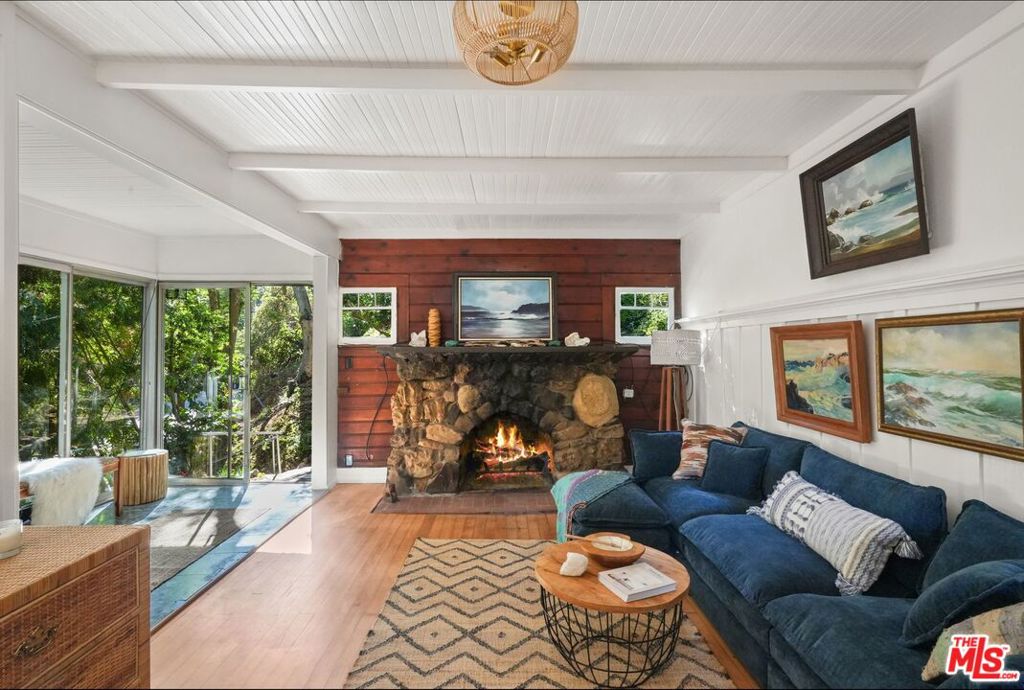 Wild Mountain Soundhouse: A Creative Sanctuary in the Heart of Topanga. Offer Deadline is Tuesday, 08/19/2025. On a peaceful hillside, where the chaparral hums and ocean air whispers through the sycamores, a singular creative sanctuary rests, unassuming, cloaked in peace, and steeped in legacy, this home stands as a quiet legend, an enduring testament to art, music, and the power of place. Known canyonwide for its giant cat statue out front, dressed for every holiday, set on 3 lots of nearly an acre of secluded, oak-shaded land and cradled by protected parkland, this one-of-a-kind Topanga retreat is where creativity finds its voice and nature becomes muse. This is no ordinary space. This is a place where music is born, where sound breathes, and where legends have gathered, not in concert halls or gilded studios, but here, in the arms of the canyon. The two-bedroom main house is a warm, soulful refuge. With original wood floors and sunlit walls of windows, the home feels less built than grown from the land itself. This is only the second time it's been on the market since 1959. The huge old stone fireplace, one of the oldest in the canyon, gives warmth and soul to the great room. The bedrooms are like tree houses, with old windows open to the wilderness. Out the back door, the patio and yard are framed by flowers, as you soak in total privacy in the hot tub. Up stone steps, a large one-bedroom guest house offers high-ceilinged comfort and privacy. Its deck has cinematic views of the Seven Sisters peaks. Lve outside on the wide deck, visited by tiny foxes and majestic hawks. The studios make this a destination for artists of all kinds. At the upper reaches of the land, far from road noise, the music studio, its walls six inches thick, its floors layered in staggered " plywood, was designed not just for quiet, but for resonance. Within, acoustic panels hush the world outside. Views are of the wild canyon, unbuilt and endless. A powder room sits below. The views invite inspiration. This space has long held the raw energy of jam sessions, rehearsals, and the soft chaos of creation. Gregory Moore of Black Flag once tuned his edge here; Noel Rhodes brought the heartbeat of Boomshaka. The late, great Malcolm Cecil, pioneer of synthesized sound and the creator of the TONTO synthesizer, left his fingerprint here. The drums that held forth here once belonged to Tommy Lee; their sound, recorded here by an ASCAAP "Man of the Year" composer, transcended the polished studios elsewhere. Rock photographer Henry Diltz, chronicler of a generation, captured a young South African prodigy in the studio. A ten-time Emmy-winning director found in this solitude the clarity to prepare for his telecasts of bands like Jon Mayall, Jefferson Starship, Asleep at the Wheel, and a dozen other icons. This is not just a studio, it is a carved-out chapel of sound and silence. A refuge for those who listen closely enough to hear the music before it's made. Nearby, another studio, offers a blank canvas for storytelling, craft, or contemplation. Decks look out over gardens, fruit trees, and golden hills. There is room for more fruit trees, more gardens, chickens, and the sustainable, nature-filled life sought by Topanga home seekers. Stone steps and forest paths wind through terraces and wild gardens. There are corners to write in, decks to dream on, and trees to listen to. Though just minutes from the heart of the canyon, and a short drive to the sea, the property feels worlds away, a sanctuary in every sense of the word. For those seeking a home that nourishes both soul and craft, Wild Mountain Soundhouse is not simply a place to live. It is a place to become.