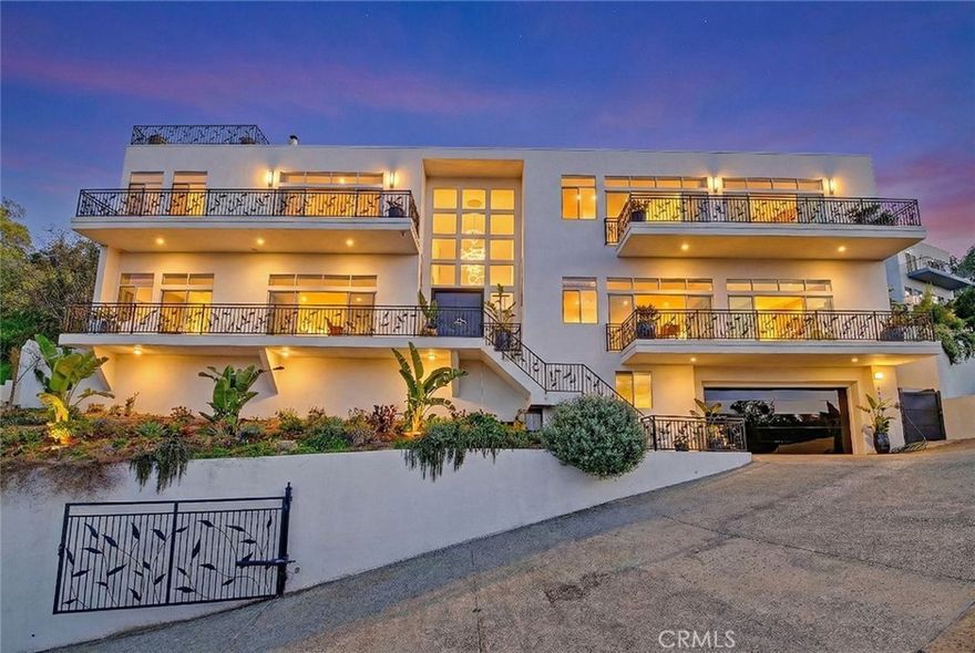 “WOW” will be the reaction from your guests, and your own emotions, when you pull up to this impressive home. You’re greeted by a massive pivot entry door and a striking 16-foot chandelier suspended from a 24-foot ceiling. Perched high in the hills of Sherman Oaks, this contemporary residence, complete with parking for up to 12 cars behind private gates, captures the perfect balance of sophistication and modern elegance, with sweeping city and mountain views filling every room. The pivot-door entry opens to a light-filled floor plan framed by 12 windows, where 24-foot ceilings and beautifully grained, stained hardwood floors create an atmosphere of refined luxury. An elevator provides effortless access to each level. The home offers 4,560 sq ft of living space with 5 bedrooms and 4.5 bathrooms, including an expansive primary suite that serves as a private retreat with a cozy double-sided fireplace, a spa-inspired tub with breathtaking views, and a dual-head steam shower. The chef’s kitchen is the true heart of the home, outfitted with top-of-the-line appliances and sleek finishes, ideal for both entertaining and everyday living. Outside, the property spans over half an acre and showcases manicured vineyard rows, fruit trees, and a French countryside–style terrace with unforgettable views that turn any conversation into a cherished moment. Each balcony offers perfectly positioned spaces to take in the panoramic scenery. Multiple fireplaces throughout add warmth and ambiance, including one that provides a cozy wood-burning experience. Don’t overlook the garage with custom polished epoxy flooring, ideal for a car enthusiast or hobbyist. Every detail of this home is thoughtfully designed for elevated luxury living, all accessible by your private elevator. Just when your guests think the tour is complete, the stunning rooftop and your own “mini Runyon” backyard hike, complete with a vineyard and 14 fruit trees, take the experience to a new level. Once at the top of the property, the full wow factor unfolds. Perfectly located above Ventura Boulevard in the coveted Sherman Oaks Hills, the home offers a sense of seclusion while remaining moments from the best of Sherman Oaks. Enjoy quick access to major freeways, high-end dining, boutique shopping, and excellent schools. Picture quiet evenings on the deck, breathtaking sunsets, and the ease of Los Angeles living paired with the elevated lifestyle of residing in the hills perched above much of the city.