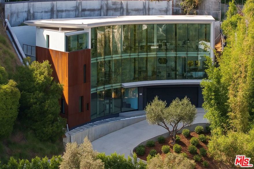 Introducing "The Curve on Thrush", a newly constructed architectural gem nestled in the exclusive Bird Streets above the Sunset Strip. Designed by the award-winning Tag Front Architects, whose portfolio includes some of the most celebrated modern residences in Los Angeles, this sculptural glass home stands as a bold expression of art, architecture, and lifestyle at the highest level. With its sweeping curved glass facade and striking steel form, "The Curve on Thrush" is more than a residence, it is a statement piece. Elevated above the city and surrounded by multi-million dollar estates, it offers absolute privacy while being moments from the very best of Los Angeles. From world-class dining and high-fashion boutiques to iconic nightlife, this home places you at the intersection of Sunset Strip energy, West Hollywood culture, and Beverly Hills luxury.Inside, the interiors unfold with dramatic scale and seamless flow. Soaring ceilings, a floating glass staircase, and expansive open-plan living areas create a gallery-like experience designed for both grand entertaining and intimate living. Every element reflects the architectural precision and material mastery that define Tag Front's work.Three luxurious bedroom suites are appointed with spa-grade finishes and filled with natural light. A private theater, elevator access, and full smart home integration elevate the living experience even further. Outdoors, a sleek pool and spa are framed by drought-tolerant landscaping, blending sustainability with serenity.A rare offering in one of Los Angeles' most coveted enclaves, The Curve on Thrush is not just a home, it is a lifestyle, a legacy, and a landmark of contemporary design.