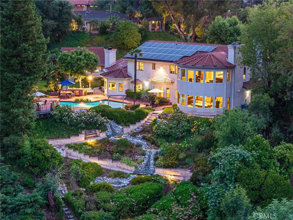 Welcome to this exceptional estate in the heart of Valencia—an exquisite, custom-designed residence offering breathtaking golf course views and resort style living. Nestled at the end of a quiet cul-de-sac, this home combines elegance with modern comfort. With 5 spacious bedrooms, 4.5 baths, and an oversized executive office, this home is perfectly designed for both relaxation and productivity. The owners expanded and redesigned the original floor plan to maximize the living space and create unbelievable views from every window. The kitchen opens to a stunning family room featuring custom wood ceilings and a beautiful stone fireplace, creating a warm and inviting atmosphere for everyday living. The expanded living room, currently configured as a game room with a built-in bar, offers the perfect setting for entertaining a large group. Expansive windows showcase stunning views of the backyard and golf course. The downstairs features a bedroom, full bathroom plus an additional half bathroom, perfect for guests. Upstairs you will find 4 additional bedrooms including the expanded primary suite, with a complete wall of windows providing yet another opportunity to take in the incredible views. Step outside to your private backyard oasis, where you’ll find a sparkling pool and spa, an outdoor kitchen and BBQ, and a built-in fireplace—all set against the picturesque backdrop of the lush golf course. The terraced hillside landscaping and private stairway access add a touch of resort-like serenity. For the car enthusiast, this property features an attached 3-car garage, an ADDITONAL detached 3-car garage (ideal for a future ADU or guest house - buyer to verify), plus a covered carport—accommodating up to 6+ vehicles with ease. Whether you’re dreaming of a private guest retreat, home gym, or income-producing unit, the potential is limitless. Enjoy peace of mind and energy efficiency with a prepaid SOLAR lease, significantly reducing utility costs. Located just minutes from major freeways, dining, shopping, local schools and parks, this home offers luxury, convenience, and lifestyle in one unforgettable package. Low HOA. No Mello Roos!! You don’t want to miss this one!