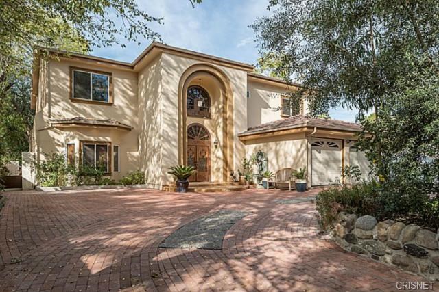Nestled on a quiet, tree-lined street, this exquisite residence was rebuilt in 2007 and offers over 6,250 sq ft of luxurious living space on a sprawling 22,804 sq ft lot. Designed for comfort and entertaining, the home features 6 spacious bedrooms, 7.5 bathrooms, and a versatile bonus room — with two bedrooms and the bonus room conveniently located on the first floor. Step through the grand double-door entry into a dramatic foyer with soaring vaulted ceilings, elegant crown molding, and a spacious formal living room with a marble fireplace. The bright, French-style kitchen is a chef's dream, showcasing custom European Craftsman cabinetry, granite countertops, a large center island, and top-of-the-line Sub-Zero and Wolf appliances. A charming breakfast area overlooks the expansive, flat backyard with a sparkling swimming pool - ideal for hosting guests or enjoying peaceful mornings. Upstairs, a custom antique wrought iron staircase leads to a gallery landing with hardwood flooring and and four deluxe bedrooms. The luxurious primary suite includes a private balcony, dual walk-in closets, and a cozy fireplace. Additional highlights include marble flooring on the first level, an integrated sound system, a fully gated semi-circular driveway, a 3-car garage, and solar panels for energy efficiency. Blending timeless elegance with modern amenities, this exceptional home is a rare opportunity to enjoy premium living in one of Woodland Hills' most desirable neighborhoods.