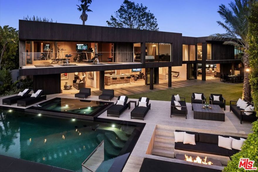 Set on a quiet hillside in Beverly Hills, this Colab House residence captures sweeping views that stretch from the city skyline to the surrounding hills. Gated and surrounded by mature landscaping, the home blends modern design with complete privacy. The main level features soaring ceilings, an open floor plan, and walls of glass that create a seamless connection to the outdoors. The chef's kitchen with high-end appliances opens to the family room, dining area, and bar, making the space ideal for both everyday living and entertaining. Upstairs, the primary suite includes a sitting area, walk-in closet, and spa-like bath with uninterrupted views. A gym, office, and guest suite complete the second floor. The backyard is designed as a private retreat, with a spacious lawn, infinity-edge pool, spa, and sunken fire pitall perfectly positioned to take in stunning sunsets. Fully automated with Savant technology, this home combines modern comfort and striking architecture in one of Beverly Hills' most desirable locations.