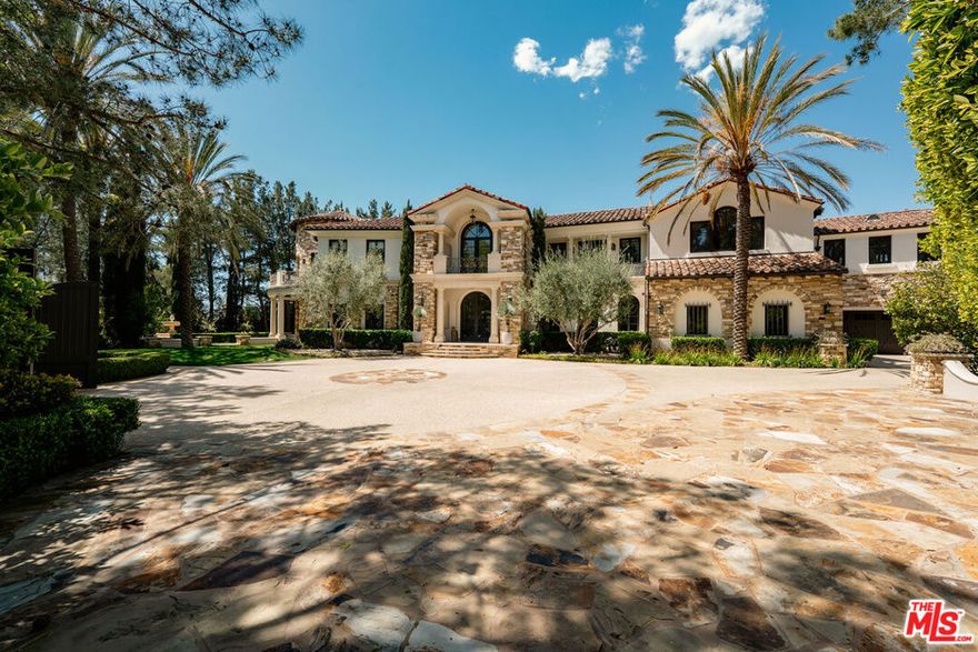 At the end of a cul-de-sac in ultra-exclusive Brentwood Country Estates lies a sprawling Tuscan residence set on manicured grounds. Guests arrive through a large iron gate and into a massive motor court, its perimeter lined with privacy hedges beneath towering palms and Mediterranean cypress. Enjoy striking panoramas of vivid green hills, canyons, and untouched mountains beyond. A lighted north-south tennis/pickleball court includes a trellis-covered viewing pavilion, basketball hoop, equipment storage shed, and a freestanding wellness gym for meditation, yoga, and fitness. Inside, a double-height foyer is characterized by a grand staircase and rich wood floors that flow into the public entertaining spaces. Host intimate gatherings in the family room, complete with fireplace and wet bar, or have tea in the formal living room, each space connected by a series of romantic archways overhead. The chic formal dining room connects to the kitchen via a butler's pantry, perfect for catering. Fit for a true gourmand, there are two islands with farm sink, state-of-the-art appliances including double Sub-Zero refrigerator, and chef-grade range with pot filler. There is also a sun-filled breakfast rotunda with multiple sets of French doors to the outside, creating an effortless indoor-outdoor flow for al-fresco living and dining. Upstairs, a sumptuous owner's wing contains a resort-inspired primary bedroom suite complete with fireplace, parlor, two large boutique-style closets, and a spa-inspired bath with floating dual-sink vanity, separate soaking tub, oversized rainwater shower, and toilet room. Secondary en-suite bedrooms are spacious and include private balconies and patios. There is also a theatre/media room for gaming and screening films, an office for work and study, and massage/spa room. At the center of the residence is an outdoor living room with double-sided fireplace flanked by dramatic archways. Additional outdoor amenities include a putting green, pool, spa, sundeck, organic vegetable and rose gardens, built-in barbecue, pathway to delightful garden swings, and numerous patios and terraces throughout. There is even a dog house with dedicated play space! Welcome to an extraordinary life of peace and comfort in a coveted guard-gated community in Lower Mandeville Canyon with 24-hour patrol, just moments to Brentwood's fine restaurants, Santa Monica's cafes and shops, world-famous beaches, and all the Westside provides.