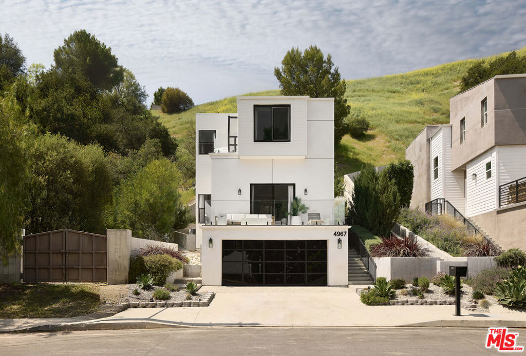 Nestled in the tranquil hills of Woodland Hills, this 2019-built modern residence exemplifies the seamless fusion of luxury and contemporary design. Located south of Ventura Boulevard, this exceptional property offers both refined elegance and intimate comfort, making it a true architectural gem. Upon entering, the home immediately captivates with its soaring ceilings and expansive, open-concept layout, flooded with natural light. Custom drapery frames the windows, adding a sophisticated touch to the space. Recessed lighting accentuates the airy atmosphere, creating a perfect balance between modernity and warmth. In a masterful play of light and texture, custom wallpaper imported from Italy delicately finished with 24k gold leaf adds a whisper of luxury and an artist's touch to the walls. The chef's kitchen, features a striking center island, a unique Mediterraneo Macchia Antica porcelain backsplash and countertops. Premium stainless-steel appliances, making it an ideal space for culinary enthusiasts. The adjacent family room, anchored by a cozy fireplace, invites both intimate gatherings and entertaining. Upstairs, the primary suite provides a luxurious retreat. The redesigned bath offers a spa-like sanctuary, complete with dual sinks, a freestanding tub, and a separate walk-in shower. A spacious walk-in closet ensures ample storage, while the private balcony presents sweeping views of the serene surroundings. The home includes two additional generously sized bedrooms, each thoughtfully designed for comfort and style. The lower level has a dedicated office/bonus room which offers flexibility for work or leisure, catering to a variety of lifestyles. The residence is equipped with the latest in-home technology, including a NEST thermostat, Sonos surround sound throughout the entire home, dual-zone air conditioning, a tankless water heater, and integrated SMART HOME features, ensuring convenience and efficiency at every turn. Unbreakable glass has been installed for added security and peace of mind. The garage has been transformed into a state-of-the-art gym, complete with high-end equipment, custom flooring, and a sauna. Ideal space for both fitness enthusiasts and relaxation. Custom finishes throughout the home include lime-wash accents, adding a unique and timeless character to the property. Situated just moments from Ventura Boulevard and Westfield Topanga, residents are within easy reach of a wealth of dining, shopping, and entertainment options, including movie theaters and chic boutiques. This Woodland Hills sanctuary is a rare find, offering a harmonious blend of thoughtful design, modern amenities, and unparalleled craftsmanship.