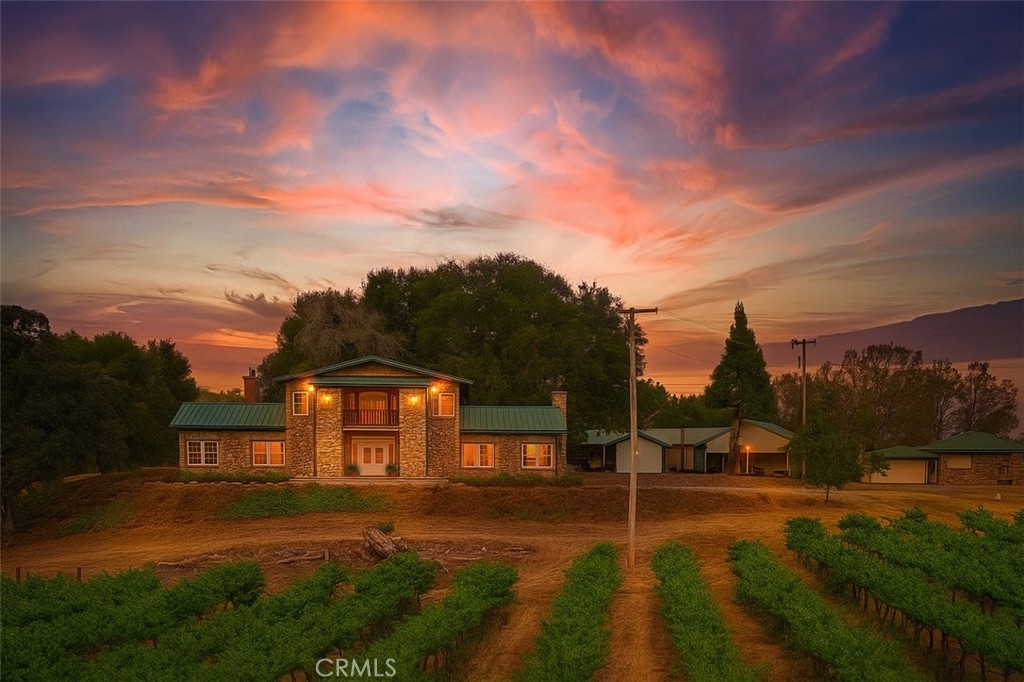 Experience the essence of refined Sierra Foothill living at the Lyons Vineyard Estate, a remarkable 28+ acre TWO HOME compound just 15 minutes from historic downtown Mariposa and less than an hour from the western entrance to Yosemite National Park. This rare property combines natural beauty, curated architecture, and established agricultural use which makes it perfectly appointed for a private retreat, boutique wine operation, or next-generation agri-luxury investment. At the heart of the property sits an elegant 5,188sf MAIN RESIDENCE, extensively remodeled in 2008 with travertine and hardwood flooring, granite countertops, and artisan finishes throughout. Negotiable in the sale are curated contents of exceptional taste, including Waterford chandeliers, fine artwork and classy furnishings, making this an unparalleled turn-key offering. A charming COTTAGE of 960sf consists of 2 bedrooms and 1 bath with a 600sf detached garage. A 704sf STUDIO-STYLE SPACE with bathroom is attached to a 4-car carport and would be ideal for conversion to a wine-country bunkhouse or Vintner's Unit. Eight acres of mature VINEYARD, four acres of Syrah and four acres of Cabernet Sauvignon, are professionally maintained and drip-irrigated via well-fed POND. The vineyard is currently under contract with Casto Oaks Mariposa Winery for the 2025 harvest, known for their award-winning 2015 Syrah (Best of Class, SF Chronicle Wine Competition). The cellar is located in the main residence at basement level and includes storage for 1,820 bottles, wine stock also negotiable in the sale. For your outdoor enjoyment, not only is there the year round pond but also two seasonal creeks with Cotton Creek offering cascading water falls and a series of stacked pools. Enjoy a glass of fine red wine on one of the balconies while stargazing and listening to the symphony of frog song at this majestic estate.