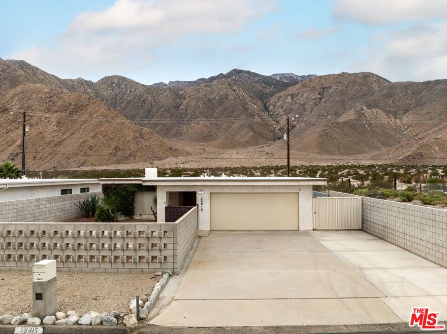 Located in the serene Windy Cove neighborhood of unincorporated Palm Springs, this home blends retro charm with thoughtful modern upgrades that celebrate its mid-century inspired architecture. Step through custom architectural metal gates and vintage double doors into an inviting open floor plan filled with natural light and uninterrupted views of the majestic San Jacinto mountain ridge. The living and dining rooms feature new high-quality hardwood panel flooring and a dramatic natural stone fireplace, the perfect centerpiece for cozy desert evenings. The efficient galley-style kitchen offers a large bar for casual dining, freshly repainted cabinetry, and updated fixtures that add a modern touch. The primary suite, showcasing beautiful mountain views, includes an en-suite bath with a vintage countertop and ample closet space. Two additional bedrooms offer generous closets, and the hall bath also featuring a vintage countertop provides easy access from the main living area. Every window throughout the home has been replaced with energy-efficient dual-pane glass and custom made sun/security shades for year-round comfort. Outdoor living is effortless with a fully enclosed front and back yard, covered patio, low-maintenance desert landscaping, and irrigation. The front breeze block patio provides privacy and style, complete with a gas fire pit ideal for stargazing on cool desert nights. Out back, under the shaded patio enjoy sunrises and sunsets that paint the sky, with wildlife often visible in the open field beyond. The two-car garage is a dream for organization lovers, featuring custom shelving, overhead storage, and an insulated door. Additional upgrades include recent roof resealing, all new light fixtures throughout, fresh interior paint, twice-yearly HVAC maintenance, vintage wallpaper accent in the laundry room with storage, gas indoor fireplace and outdoor gas grill for easy entertaining. Just 6 minutes from downtown Palm Springs, you'll enjoy the best of both worlds, peaceful desert living with quick access to shopping, dining, nightlife, and endless outdoor recreation. Listen to coyotes under the stars, spot riders on nearby horse trails, and experience the authentic desert lifestyle from the comfort of this thoughtfully updated mid-century inspired gem.