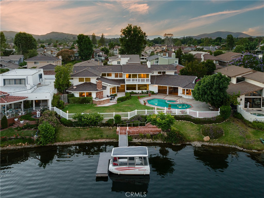 A Hidden gem, Rare Double Lot. This property is within the prestigious guard gated community of Westlake Island, an oasis of beauty & sophistication nestled in the heart of Westlake Village. With over 100 feet on the main channel with breathtaking panoramic views of the marina,
rolling hills, and Yacht Club. Situated on a 11,250 sq ft lot, this estate offers unmatched serenity, privacy, and remarkably generous parking. Step inside and experience the natural light streaming through picture windows, illuminating a blank canvas ready to be reimagined into your dream California indoor-outdoor lifestyle. The primary features picturesque windows that showcase the stunning lake and mountain range. The suite also has space for an elevator from the office below. The secondary bedrooms are oversized, conveniently situated near the upstairs laundry room. Outside, indulge in resort-style living with a sparkling pool, spa, built-in BBQ, and a lush grassy yard dotted with mature fig, avocado, and grapefruit trees. Private dock access means sunset cruises and lakeside dinners are only steps away. Nestled in a 24- hour guard-gated community that blends luxury, convenience, and natural beauty, this is more than a home its a lifestyle.