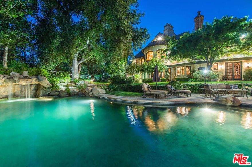 Now offered at $6,750,000 after a $500,000 price reduction, this timeless French-inspired chateau sits behind double iron gates on more than ten private, park-like acres within the exclusive enclave of Cold Creek Estates in Calabasas. Surrounded by the breathtaking natural beauty of the Santa Monica Mountains, the estate is a masterpiece of Old World elegance, refined craftsmanship, and unmatched tranquility. Spanning over 11,000 square feet, every detail of this custom residence has been thoughtfully designed and meticulously executed, from hand-distressed white oak flooring and intricately beamed ceilings to solid wood doors with imported French hardware. As you arrive through the stately motor court, a grand entry welcomes you into a soaring foyer that flows seamlessly into a dramatic garden-room conservatory, offering the first glimpse of the lush grounds that frame this exceptional property. The estate offers six expansive bedroom suites and eleven thoughtfully appointed bathrooms, complemented by a subterranean stone wine cellar with tasting room, a media and poker lounge, a spacious gym with private sauna, and a distinguished formal library with bespoke cabinetry. The chef's kitchen is a true culinary dream, featuring a La Cornue range, a full-sized Sub-Zero refrigerator and freezer, dual walk-in pantries, double ovens, warming drawer, and dual dishwashers. A grand center island provides a dedicated baking station, prep sink, and breakfast bar, creating the perfect space for both everyday living and gourmet entertaining. Just beyond, a sunlit breakfast nook and adjoining den with fireplace offer intimate spaces to begin or end each day. Upstairs, the primary suite presents a private sanctuary, complete with three fireplaces, a sitting area, volume coffered ceilings, and a private balcony overlooking the estate. The spa-like bathroom is designed for indulgence, with dual vanities, a soaking tub, a warming fireplace, and an expansive dressing room featuring dual walk-in closets and a large makeup vanity. Three additional en-suite bedrooms complete the second level, ensuring comfort and privacy for family and guests alike.The outdoor living spaces are equally enchanting, evoking the ambiance of a private resort. A dramatic infinity-edge pool with waterfall grotto is accompanied by a spacious poolside pavilion with built-in barbecue, stone-surround fireplace, bath, and changing room. The meticulously landscaped gardens include a colorful English rose garden, vine-draped gazebo, koi pond, greenhouse, and citrus orchard, all connected by meandering pathways that invite exploration and quiet reflection. Additional features include an elevator servicing all levels, a guest or caretaker's cottage, a rooftop observatory, ten uniquely designed fireplaces, an imported slate roof, and a four-car garage. From its unparalleled craftsmanship and luxurious amenities to its serene natural surroundings, this French-inspired chateau offers a truly extraordinary opportunity to own a residence that seamlessly blends timeless elegance with the best of California living.