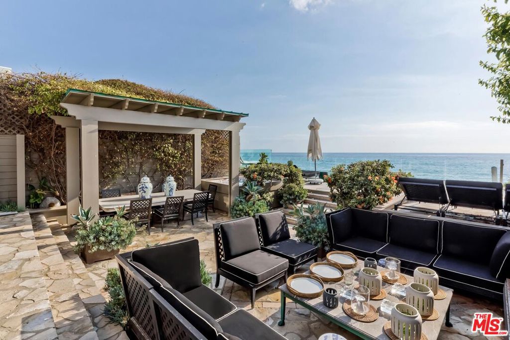 This meticulously restored and modernized Country English-style Malibu Colony beach home has graced the cover of Architectural Digest and sits on approximately 34 feet of pristine beach frontage. The open floor plan is luxuriously furnished, featuring a gourmet kitchen that seamlessly flows into the living room with a fireplace and vaulted wood-paneled ceilings throughout. A sun-filled loft above the living room offers sweeping views of the Colony beach. The elegant primary suite includes a cozy sitting area, a walk-in closet, and a beautifully appointed bathroom. Additionally, there is a separate attached private guest bedroom with an ensuite bathroom. The expansive deck and outdoor patio are ideal for dining and entertaining, showcasing multiple dining areas, a spa, outdoor shower, BBQ, and an outdoor fireplace. This is a rare opportunity to live in one of Malibu's most exclusive and highly sought-after guard-gated communities, just moments from the area's premier shopping and dining.