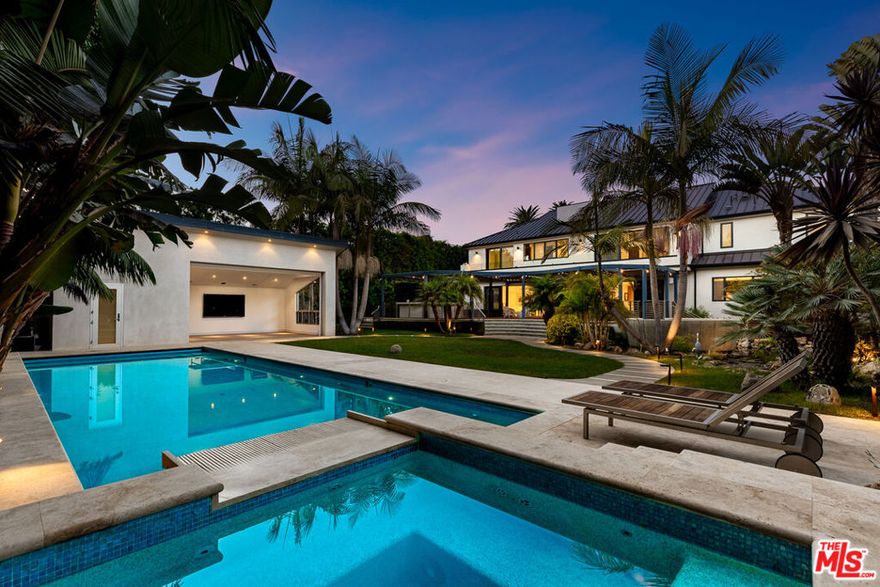 A significant price adjustment promises amazing value! In the coveted, prestigious Palisades Riviera rests a pristine resort-inspired coastal architectural, surrounded by lush landscaping on oasis-like grounds that offer a blend of soothing natural elements and serene outdoor leisure spaces. Inside, natural light fills the double-height foyer that opens to the public entertaining areas. A commanding floor-to-ceiling fireplace partitions the family room and formal living room, each fitted with walls of sliding glass that frame vivid greenery. Nearby, the formal dining room is perfect for intimate gatherings and celebrations. The sleek, modern kitchen is appointed with custom imported cabinetry, Miele appliances, center island with prep sink, and breakfast bar. On the second level, positioned central to the bedrooms, is a private patio with treetop views adjacent to the pajama room. The oversized primary suite has lofty ceilings, custom built-ins, a makeup station, walk-in closet with shelving. A balcony connects the main bedroom to the lavish bath equipped with a floating wraparound vanity, separate soaking tub, and large rainwater shower. In the backyard, enjoy an abundance of amenities such as a sprawling lounging deck with brand-new retractable awning, overhead heaters, and outdoor kitchen with commercial-grade pizza oven, barbecue, and bar ledge. There is plenty of grassy space to play, a sparkling pool, spa with water feature, and a spacious pool house/cabana with flat screen, poolside shower, and bathroom. A wall of privacy hedges and tropical plantings provides utmost seclusion and peace. The serene waterfall fills a tranquil pond, replete with blossoming lily pads, that encircles the fire pit for casual evenings under California skies. Located on D'Este Drive, one of the most highly desired, non-through streets with a park-like feel, this home is just moments to the Riviera Country Club, tennis club, hiking trails, and all that makes life here so pleasant. Enjoy close proximity to award-winning schools, top-rated restaurants, boutiques, beaches, and the best of the Westside. Welcome!