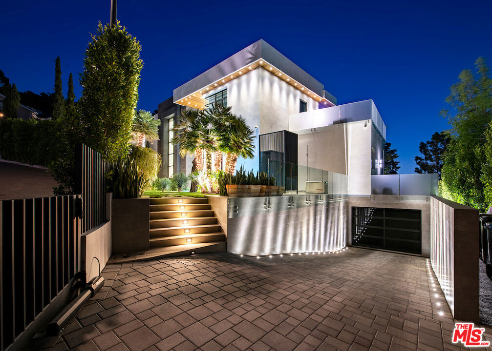 Contemporary private estate boasting impeccable interiors, breathtaking canyon views, city lights, an elevator, and an extraordinary 7-car showroom garage. Nestled in a serene locale free from through traffic, featuring ample street parking for guests, and mere minutes from the Beverly Hills Hotel. The master suite offers a private living area or study, a dual-sided bath with marble shower and soaking tub, remarkable his/her walk-in closets, and a secluded outdoor deck for al fresco movie nights or games. Upstairs, two additional exquisite suites feature multiple spacious decks and an office/library area. Downstairs, find two more suites and a lower level with a grand screening room leading to a sports and party room complete with a bar. Abundant storage, including an 800+ bottle wine cellar, and a private guest entry ensure seamless hospitality. Enjoy resort-style living with a stunning large swimming pool, full outdoor barbecue kitchen with pizza oven, expansive deck areas, and wrap-around yard space for children and pets. A truly exceptional family retreat, replete with every luxury imaginable.