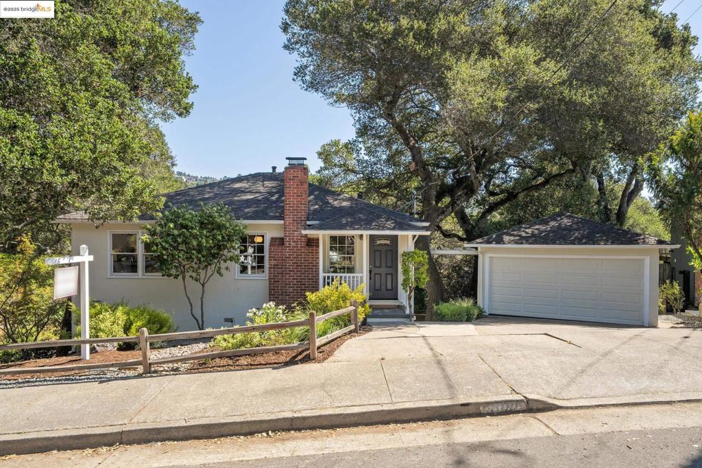 This inviting two-story retreat on a spacious, tree-filled corner lot, feels worlds away yet close to everything. The level-in main floor offers two bedrooms and a full bath, plus an airy living-dining room with a fireplace. The eat-in kitchen provides ample cabinet space and a serene private view—perfect for enjoying morning coffee. The lower level features a private primary suite with a large walk-in closet, laundry room, ample storage, and a comfortable den for relaxation or work. Upgrades include newer AC, furnace, 200-amp electrical panel with EV charger, double-paned windows, and a seismic retrofit. Outdoors, enjoy multiple seating areas, a hot tub, and a fenced yard shaded by graceful oaks, along with a detached two-car garage and a large driveway ideal for projects—all just minutes to Montclair Village and blocks from Redwood Elementary, parks, trails, and freeway access.