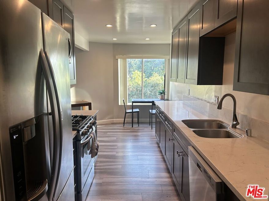 Stylish new flooring flows into an updated kitchen featuring quartz countertops, soft-close cabinetry, and stainless-steel appliances. The inviting living room includes a cozy gas fireplace and a built-in entertainment center. The bathroom offers a modern vanity with hidden plug access, while the bedroom is complete with a spacious walk-in closet. Recessed lighting has been recently added throughout, and the home is equipped with central heat and air. Each floor of the building, including the ground level, provides a laundry room with free washer and dryer access. Additional highlights include two covered tandem parking spots and a shared outdoor recreation area with a barbecue grill. This quiet, well-kept 14-unit complex is just a short stroll to the trendy shops and dining of Tujunga Village.