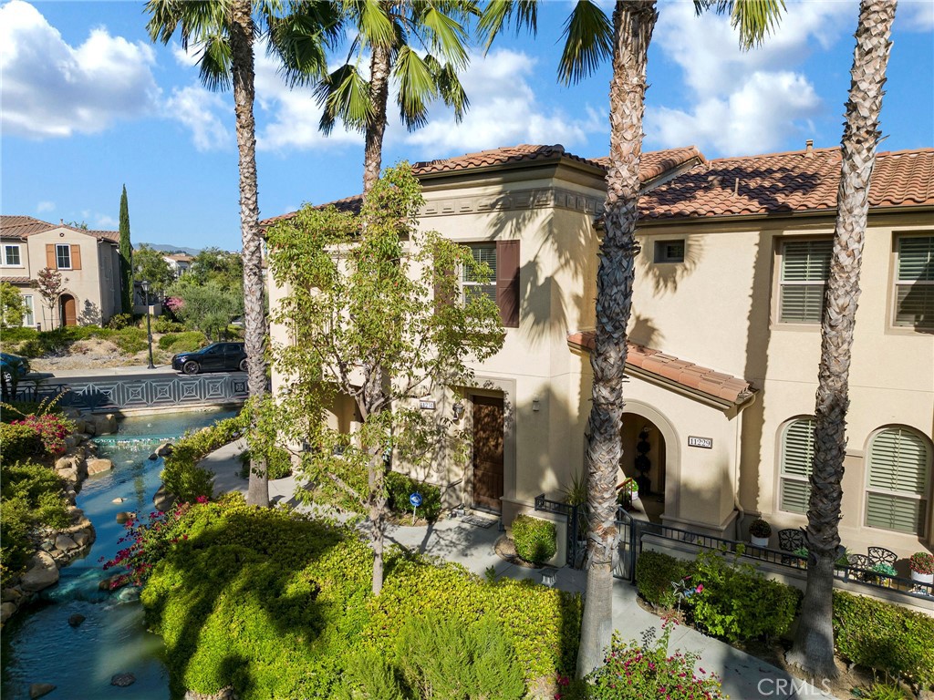 Upgraded Waterfront Luxury in the Guard-Gated Aldea Neighborhood! This townhome is one of only 20 homes in Aldea with a waterfront location making it one of the most sought-after locations in the community. Just a few steps from your front door, you’ll be greeted by the sound of cascading water from the waterfall. The entryway features checkered flooring, setting a refined tone as you step inside. On the first floor, you’ll find direct access to the attached 2-car garage, a separate laundry room with storage, and the welcoming foyer. Head upstairs, and to the right you’ll discover a the secondary bedroom and full bath. Straight ahead, a hallway opens to the heart of the home: an open-concept kitchen, dining area, and family room with a cozy patio. The kitchen is upgraded with granite countertops, stainless steel appliances, and ample cabinet space, all flowing seamlessly into the bright living and dining areas. At the far end of the home sits the corner primary suite, offering both privacy and light. The en-suite bathroom has been fully remodeled with a spa-style shower, creating a luxurious retreat. Throughout the home, you’ll notice thoughtful upgrades including hand-scraped hardwood floors, elegant upgraded crown moulding, door trims, baseboards, and lighting fixtures. Living in Aldea means enjoying resort-style amenities: a sparkling pool, spa, BBQ area, and lushly landscaped grounds — all just minutes from The Vineyards at Porter Ranch, top-rated schools, hiking trails, and freeway access. Don’t miss this chance to own one of Aldea’s exclusive waterfront homes — only 20 exist in the entire 500-home community!