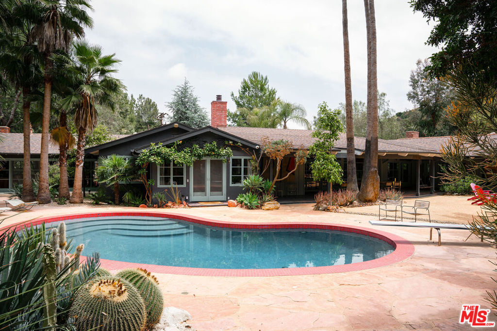 Featured in Architectural Digest, this spectacular artist compound, originally created by visionary Ed Ruscha, is truly a quintessential urban oasis. Situated on a corner lot combining two California Ranch houses, this gated estate sits on almost two acres of land in Brentwood. The two 1950's ranch structures were joined, creating an impressive great room, with high ceilings, from the space between, now ordained by a prominent fireplace with oversized windows and doorways connecting to the front and rear. The world class California landscape and pool having been the inspiration for much of Ruscha's profound art. Currently, the floor plan offers three spacious bedroom suites plus public spaces, including a seductive library, a respectable formal dining room, family and living rooms all anchored by a farm-style eat-in kitchen. All the rooms face the succulent cactus gardens, fountains and the romantic California pool. Away, up a meandering path, from the main structure sits an autonomous one bedroom, with porch, guest house. Beyond the guest house, the authentic meditation studio delineates the end of the grounds. The property's modern 60's vibe is flooded by California light and blue skies.