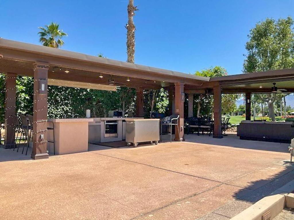 This premium south-facing lot on quiet Divit Court offers mountain views, no harsh sun or strong winds, a north-facing coach for cooling, and a private outdoor space with a solid roof, power screens, fountain, wicker furniture, full kitchen, BBQ, Smart TV, and ceiling fans. Located in the sought-after Outdoor Resort Indio, this luxury RV lot also features a wide, unobstructed golf course view and a large L-shaped pergola with a fluted aluminum solid roof. The spacious L-shaped outdoor kitchen includes granite countertops, stainless appliances, a four-burner cooktop, oven, dishwasher, fridge, wine fridge, and stainless storage. Four electric screens and one manual screen offer versatile shade and privacy, while three ceiling fans, coated RV pad, and extensive pergola lighting enhance comfort. A 55' mounted Smart TV, WiFi hotspot, beautiful landscaping with a Meyer lemon tree, and recently upgraded low voltage wiring ensure convenience and style. Two 4000-watt Infratech ceiling heaters, currently in storage, are also negotiable for added luxury.‍Outdoor Resort Indio is a Class A only RV resort in Indio, CA.