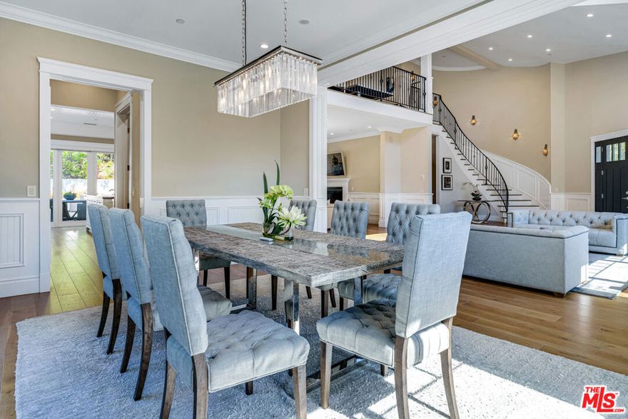 Elegant East Coast inspired gated residence in Tarzana, built in 2014, situated on an expansive 18,000+ sq ft lot. This designer-perfect home showcases quality craftsmanship throughout, featuring brushed white oak flooring, recessed lighting, Restoration Hardware wall sconces, and custom details. Offering 5 bedrooms (one currently used as an executive office/library) and 4.5 baths, the residence blends comfort with sophistication. The open chef's kitchen is designed for both daily living and entertaining, with quartz countertops, a large granite-topped island, top-of-the-line stainless steel appliances including a 6-burner range with pasta faucet, and a butler's pantry. Adjacent to the kitchen is an oversized formal dining room and a spacious living room highlighted by a dramatic two-story ceiling. The main level also includes a guest bedroom suite. Upstairs, a versatile sitting area offers hillside views, along with a convenient laundry room with sink. Two additional en-suite bedrooms complement the elegant primary suite, which boasts dual walk-in closets and a spa-inspired bath with a freestanding Midocean soaking tub, walk-in shower, dual vanities, and makeup counter. The large family room seamlessly connects to a resort-style backyard with a remote-controlled saltwater pool and spa, built-in BBQ island, fire pit, and expansive patio ideal for outdoor entertaining. Additional highlights include a two-car garage with space for a third vehicle, custom window coverings, dual-zoned HVAC, energy-efficient double-panned windows, LED lighting, and a security system with cameras. Conveniently located near The Village, Ventura Boulevard dining and shopping, Warner Center, local parks, and freeway access.