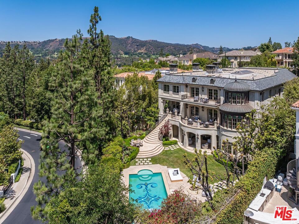 Tucked behind gates in the prestigious enclave of Bel Air Crest, this reimagined French Contemporary estate by Richard Landry is a masterwork of scale, serenity, and architectural refinement. Completed in 2004 and spanning approx. 13,100 square feet, with 7 bedrooms/8 full bathrooms + 2 powder rooms, the residence is a harmonious blend of California light and timeless European elegance. A dramatic double-height foyer with a sweeping staircase, skylight and Crema Marfil limestone floors sets the tone. Venetian plaster walls in sun-washed tones, detailed moldings, crystal chandeliers, and finely milled paneling establish an atmosphere of quiet luxury. Expansive formal spaces include a richly paneled library with fireplace, grand living room, a formal dining room, and sleek bar lounge ideal for entertaining. At the center of the home, a showpiece chef's kitchen impresses with top-tier appliances, marble counters, a large center island, and a rotunda-style breakfast room framed by curved steel windows. The primary suite offers refined comfort, with a secluded sitting room and fireplace, curved glass reading nook, private terrace, custom walk-in closet and large center island, and dual marble-clad baths with a resort-like feel. Upstairs are three spacious guest suites, each with en-suite baths and walk-in closets and an upstairs laundry room. One features an attached skylit nursery inspired by Korean design. The lower level is dedicated to elevated wellness and relaxation, featuring a mirrored gym with commercial-grade equipment, private sauna, and steam shower all with direct access to the tranquil pool terrace. A state-of-the-art theater, wine vestibule/cellar, two guest/staff suites, pool lounge bedroom with full bath and walk-in closet, and full-service laundry/mudroom complete the level. The four-car garage includes custom storage and a central vacuum. A true extension of the home's elegance, the outdoor spaces are reminiscent of a private resort featuring a mosaic-tiled pool and spa, manicured hedges, limestone pavers, and mature olive trees surrounding a series of serene terraces. A stone staircase leads to an al fresco pavilion with fire pit and built-in BBQ/kitchen are a perfect for entertaining or quiet retreat. Additional features include an elevator to all levels, smart home technology, double-gated motor court, a hand-made stone facade and located at the end of a secluded cul-de-sac. HOA Amenities: private clubhouse with a fitness center, tennis and basketball courts, putting green, and a resort-style pool and spa. Additional amenities include a playground, dog park, scenic trails, and 24/7 security patrol offering comfort, wellness, and peace of mind. Every detail of this exceptional estate reflects a commitment to timeless luxury, effortless living, and the highest standard of design in one of Bel Air's most coveted gated communities.