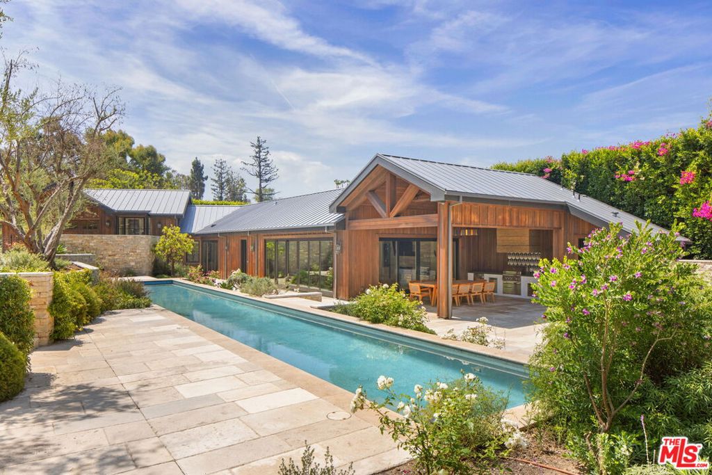 Set behind reclaimed oak gates on a rare acre of ultra-private grounds, this remarkable Pacific Palisades offering presents an extraordinary opportunity to build a dream-worthy estate just minutes from the coastline. Spanning two adjacent parcels, this secluded compound blends exclusivity, natural beauty, and architectural pedigree -- positioning it as one of the most compelling redevelopment opportunities on the Westside. Prior to the recent wildfire event, the site was home to an ~8,500-square-foot main residence and a ~2,400-square-foot guest house, both completed in 2021 with exquisite detail. While the main residence was lost, the guest house and the majority of the impeccably curated grounds remain intact, offering a meaningful foundation for a legacy estate. Nestled among mature trees and lush landscaping, the standing guest house is a vision of understated luxury. Rustic charm meets modern refinement with vaulted, beam-lined ceilings, a stone-clad fireplace, and sunlit living spaces that open to the surrounding gardens and terraces. The gourmet kitchen is impeccably outfitted with top-tier Viking appliances, built-in wine storage, a stone-topped peninsula, and a walk-in pantry -- ideal for entertaining in style. Two gracious en-suite bedrooms are complemented by a powder room, laundry room, infrared sauna, and a 2-car garage with direct access. Thoughtful finishes, organic textures, and seamless indoor-outdoor transitions speak to a design philosophy centered on comfort, wellness, and timeless quality. The lush, park-like grounds are a marvel in their own right. At the heart of the estate lies a 70-foot ozone lap pool, spa, and cold plunge -- designed for both relaxation and revitalization. A covered outdoor kitchen and dining pavilion is ideal for entertaining year-round, while raised gardens and a grove of 50+ year-old olive trees imported from Napa offer peace, privacy, and pastoral charm. Included in the sale: Architectural plans for the former main residence, landscape and hardscape design plans, final debris removal certificate, and debris assessment and sampling reports. Whether you envision recreating the estate's former grandeur or designing something entirely new, this offering provides an invaluable head start -- saving time, energy, and hurdles for the next owner. Few properties in Pacific Palisades combine this level of privacy, scale, architectural value, and coastal proximity. This is more than a development site -- it's a canvas for legacy creation in one of the Westside's most coveted enclaves.