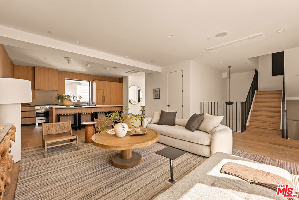 Introducing three newly built townhomes in the vibrant heart of Mid-City - each thoughtfully crafted with a refined design sensibility and an eye for modern luxury. Every residence showcases bespoke finishes and architectural details, including custom lighting, wood-paneled accent walls, and Roman clay plaster accents that provide warmth and sophistication throughout. Unit A boasts a private entry foyer with soaring ceilings, leading directly to a lower-level en-suite guest bedroom with sliding doors - ideal for a home office or gym space. The main level is designed for everyday comfort and entertaining, featuring an expansive living area with an abundance of natural light, a chef's kitchen with stainless steel appliances, an oversized island with breakfast bar, and a dining area framed by sliding glass doors. Upstairs, the primary suite serves as a tranquil retreat, complete with a spa-inspired ensuite bathroom featuring dual vanities, a stunning walk-in shower, and a custom-built walk-in wardrobe. Two additional guest bedrooms and a full shared bath provide ample space for family or guests. The top-level boasts an incredibly spacious flex space perfect for a media lounge, game room, or private home office, with the added convenience of a guest bath and built-in storage. Sliding doors lead to an expansive, covered rooftop terrace, offering sweeping panoramic views of Downtown Los Angeles, the Hollywood Hills, and beyond - an unbeatable backdrop for entertaining or relaxing. These residences embody elevated Mid City living - where thoughtful design, high-end finishes, and breathtaking views come together seamlessly.