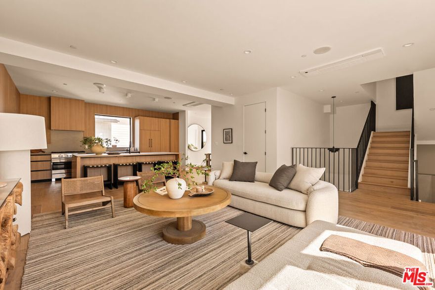 Introducing three newly built townhomes in the vibrant heart of Mid-City - each thoughtfully crafted with a refined design sensibility and an eye for modern luxury. Every residence showcases bespoke finishes and architectural details, including custom lighting, wood-paneled accent walls, and Roman clay plaster accents that provide warmth and sophistication throughout. Unit A boasts a private entry foyer with soaring ceilings, leading directly to a lower-level en-suite guest bedroom with sliding doors - ideal for a home office or gym space. The main level is designed for everyday comfort and entertaining, featuring an expansive living area with an abundance of natural light, a chef's kitchen with stainless steel appliances, an oversized island with breakfast bar, and a dining area framed by sliding glass doors. Upstairs, the primary suite serves as a tranquil retreat, complete with a spa-inspired ensuite bathroom featuring dual vanities, a stunning walk-in shower, and a custom-built walk-in wardrobe. Two additional guest bedrooms and a full shared bath provide ample space for family or guests. The top-level boasts an incredibly spacious flex space perfect for a media lounge, game room, or private home office, with the added convenience of a guest bath and built-in storage. Sliding doors lead to an expansive, covered rooftop terrace, offering sweeping panoramic views of Downtown Los Angeles, the Hollywood Hills, and beyond - an unbeatable backdrop for entertaining or relaxing. These residences embody elevated Mid City living - where thoughtful design, high-end finishes, and breathtaking views come together seamlessly.