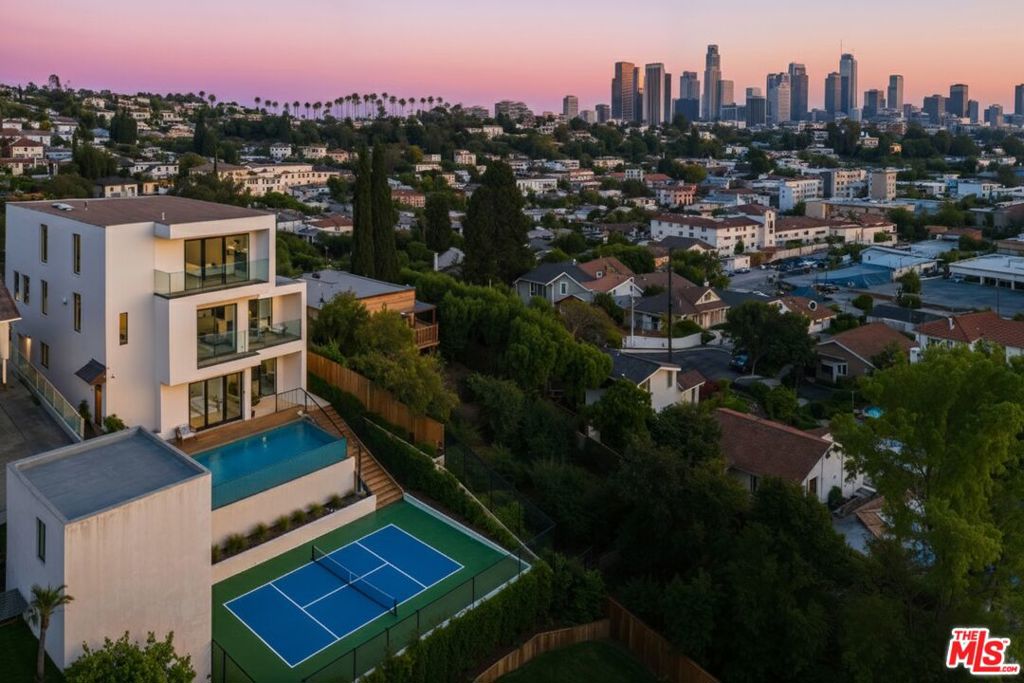 Welcome to the "NELA Observatory", a breathtaking new construction that blends mid-century modern inspiration with today's finest design and functionality, set on a private and peaceful cul-de-sac with jetliner views of DTLA and the surrounding mountains. Every level of this three-story residence was crafted to capture sweeping sunsets and shimmering city lights. The entire lower level is a private two-bedroom, one-bathroom ADU with its own address and entrance, complete with an open-concept kitchen, laundry, multiple balconies, and unobstructed vistasideal as an income-generating rental, guest quarters, or space for loved ones. Upstairs, the main residence features three bedrooms and three bathrooms, including a serene primary suite with a private veranda overlooking Echo Park Lake, downtown, and the Hollywood Hills, plus a spa-inspired bath with soaking tub. The main level is designed for entertaining with floor-to-ceiling windows, wraparound balconies, and views of the Hollywood Sign on clear days. A chef's kitchen with Viking appliances, generous counter space, and seamless flow into the living areas anchors this floor, complemented by an office or fourth bedroom with its own bath. Altogether, the home offers six bedrooms and five bathrooms, a two-car garage, additional driveway and street parking, and a clean, gated entryway. For outdoor enthusiasts, the property is walking distance to Elysian Park's hiking trails and just minutes from Griffith Park, Dodger Stadium, and Sunset Blvd. Local favorites like Valerie Bakery, Canyon Coffee, and Glowing Plant-Based Eatery are nearby, along with Stronghold Climbing Gym, wellness centers, and EV charging stations. Adding even more appeal, conceptual renderings are showcased for a pool, pool deck, and sport court, highlighting the incredible potential of the outdoor spaces should a buyer choose to develop them. Offering endless opportunities for relaxation and adventure, the NELA Observatory is hillside living at its most inspiring.