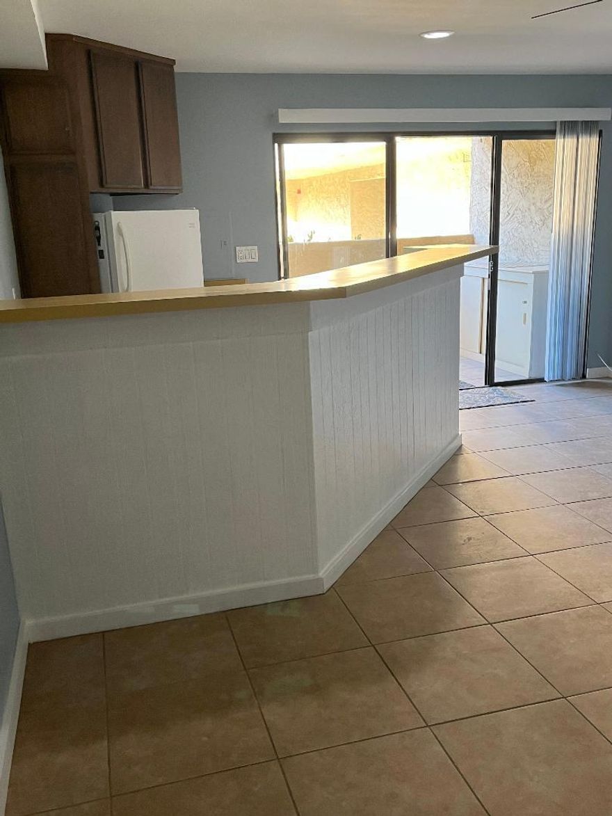 This super cute Jr. 1 bedroom ground floor unit has tile throughout the home. The kitchen has a full breakfast bar that surrounds it and is completely open to the great room which is fantastic for entertaining your friends and family. There is a large walk in closet off of the bedroom that you can access from either the hallway or bath. The bedroom will accommodate a full size or twin bed. The AC unit is brand new. There is a sliding glass door that opens to the exterior covered patio that host views of the green belt and mountains,  You are steps away from the nearest pool/spa and the laundry facility is literally across the hallway from your front door. Wifi, basic cable, water and trash are included. The tenant pays for gas, electric and any upgrades to wifi/cable.  Conveniently located in South Palm Springs. Call today to book a showing.