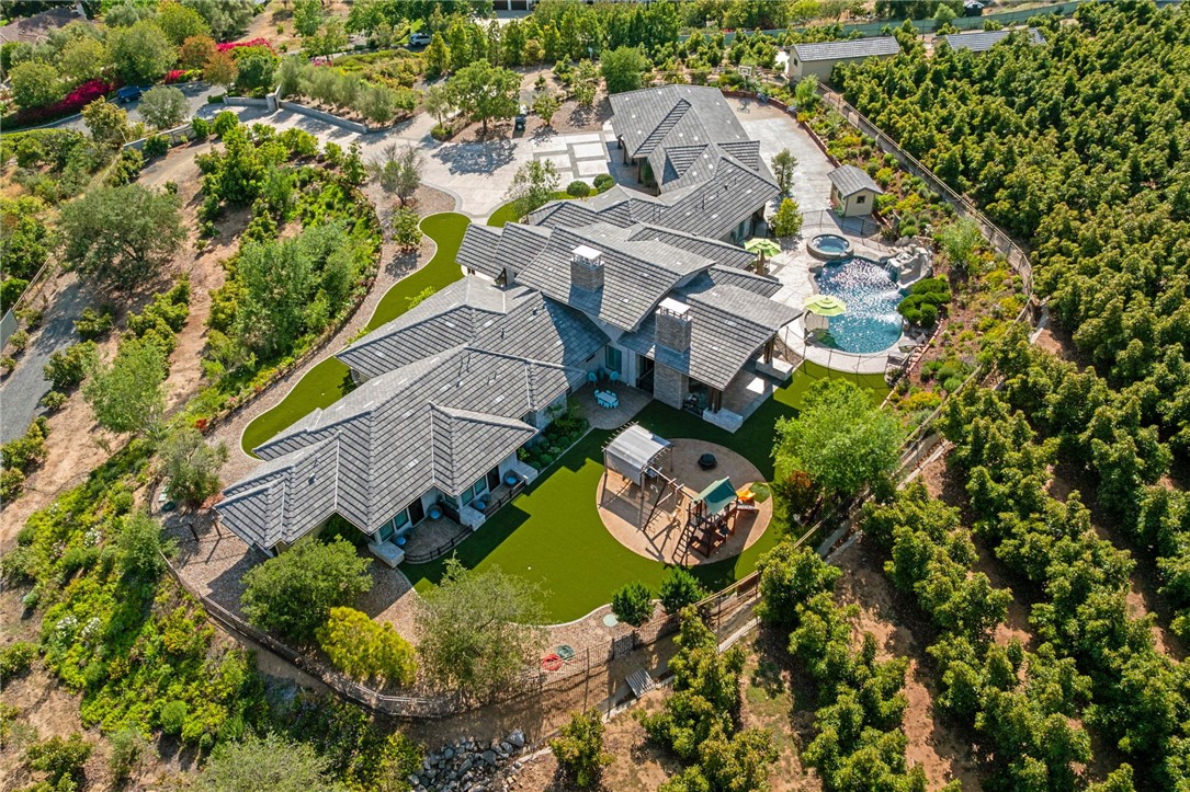 Welcome to 45166 Oak Manor Court – A One-of-a-Kind Custom Estate in De Luz Tucked away on the exclusive cul-de-sac of Oak Manor Court, this one-of-a-kind 2020 custom-built estate offers the perfect blend of luxury, privacy, and thoughtful design—no detail has been overlooked. Located in the heart of De Luz and surrounded by only three other beautifully crafted custom homes, this property sits on nearly 5 acres of fully landscaped land, offering complete tranquility and sweeping scenic views. The grounds are a private oasis, featuring a lush avocado grove with over 700 trees, mature trees, fruit trees, vibrant plants, manicured turf, and a resort-style pool and spa. Enjoy summer days on the water slide, under color-changing lights, or relaxing in the pebble tech pool. A private full bathroom serves the pool area for maximum convenience. The outdoor amenities continue with a custom outdoor kitchen and entertaining area, complete with vaulted wood ceilings, concrete accents, automatic wind shades, and a spacious patio with fireplace and ceiling fan—ideal for year-round hosting. On the opposite side of the home, a second outdoor patio opens to the interior via dramatic floor-to-ceiling panel doors, blending indoor-outdoor living at its finest. Children will love the large play set and a charming third shed designed as a playhouse, which can also function as a home office or additional storage space. Two additional large matching storage sheds offer plenty of room for tools, toys, or equipment. Inside, the home features soaring vaulted ceilings and designer finishes throughout. The chef’s kitchen is a showstopper with dual oversized islands, abundant cabinetry, and seamless flow into the spacious family room with pitch wood ceilings and direct backyard access. The home includes two luxurious master bedroom suites. Each of the four spacious bedrooms includes its own en-suite bathroom, and two rooms enjoy private gated patios. An oversized dedicated office adds versatility to the floor plan, along with a total of 5.5 bathrooms. This fully fenced estate includes a private electric gated entrance, backup Kohler generator connected to the main panel, and is just 10 minutes from the freeway and shopping. Whether you're entertaining, relaxing, or simply enjoying the peaceful De Luz lifestyle, this property delivers unmatched quality and value. This is more than just a home—it's the best custom estate on the market in De Luz. Don’t miss this rare opportunity.