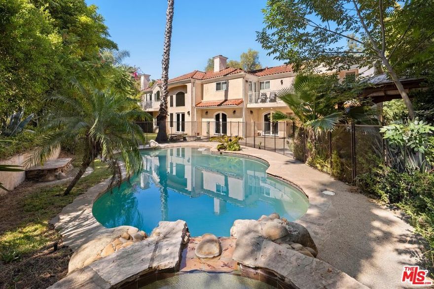 Stunning gated estate located South of the Blvd on prestigious Vanalden Ave. This private and stately home offers soaring vaulted ceilings, dramatic dark wood floors, and an open layout ideal for entertaining. The grand living room features floor-to-ceiling windows creating an abundance of natural light with views of lush greenery and a sparkling saltwater pool. A dramatic second-floor mezzanine overlooks the spacious living room, adding architectural elegance and a sense of grandeur. The home includes a formal dining room, cozy den with fireplace next to the kitchen, and a separate sitting or game room off of the living room. The chef's kitchen boasts high-quality Imperial appliances, a built-in refrigerator, stone counters, center island, and a breakfast nook with French doors leading to a resort-style yard. The backyard oasis includes a heated pool and spa, built-in BBQ, gazebo, fire pit, and child safety gate. The first floor has two bedrooms, offering an ideal spot for an office. The second floor features four large bedrooms, including a luxurious primary suite with dual walk-in closets, a spa-style bath with steam shower, jetted tub, and marble finishes. One bedroom serves as a home theater with balcony access completing the upper level. This is a unique opportunity to own a beautifully designed residence in one of the most sought after areas in Tarzana.